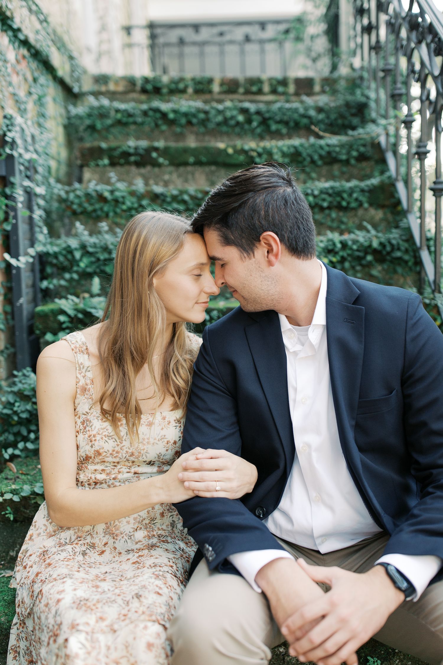 Intimate couple moment on ivy-covered stone steps during engagement photoshoot.