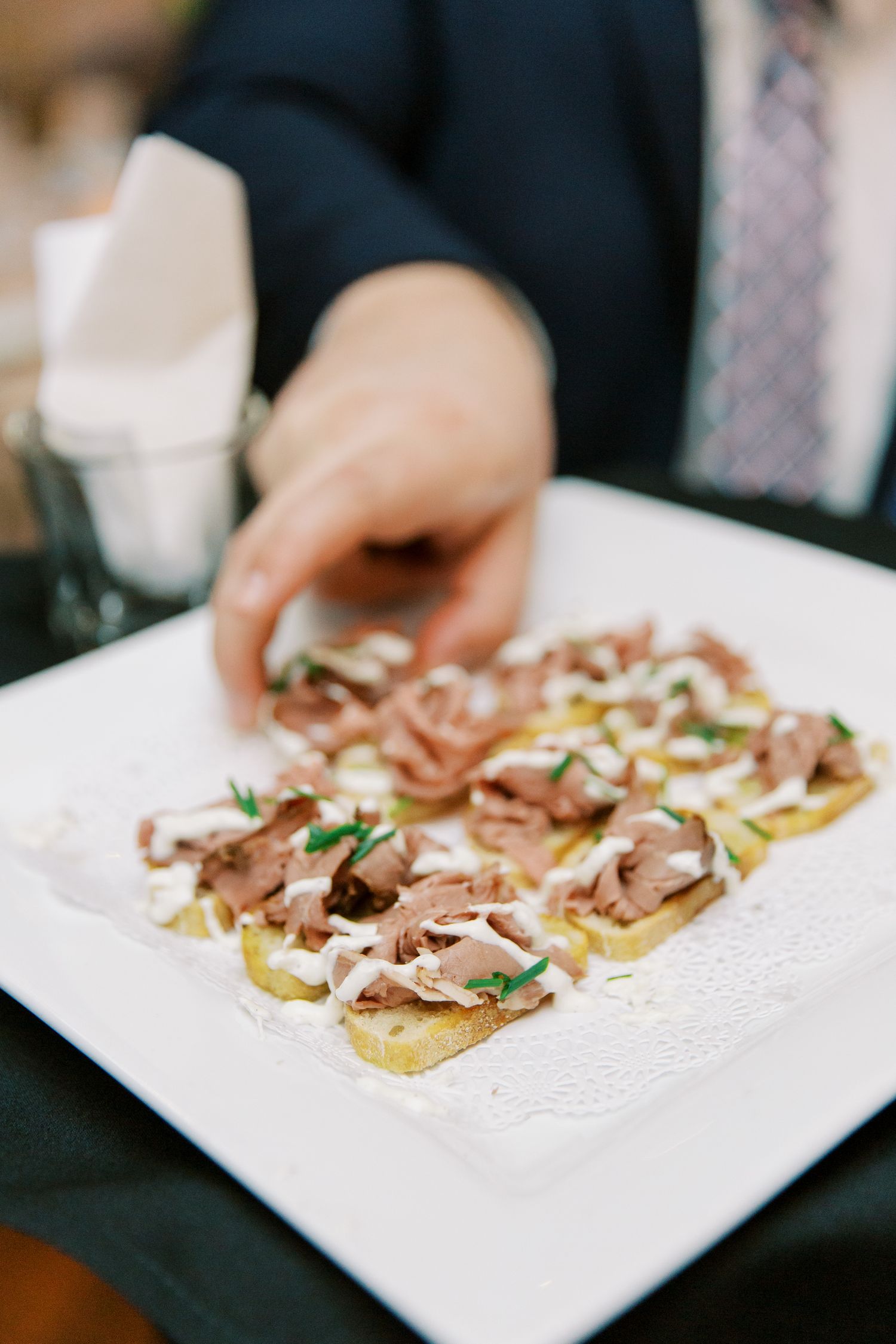 Elegant appetizers featuring thinly sliced meat and garnish served on a white rectangular plate.