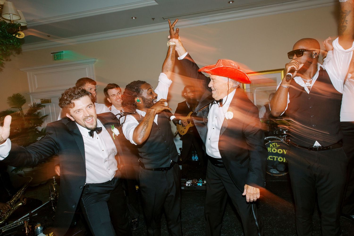 Energetic wedding reception party with groomsmen celebrating on dance floor.