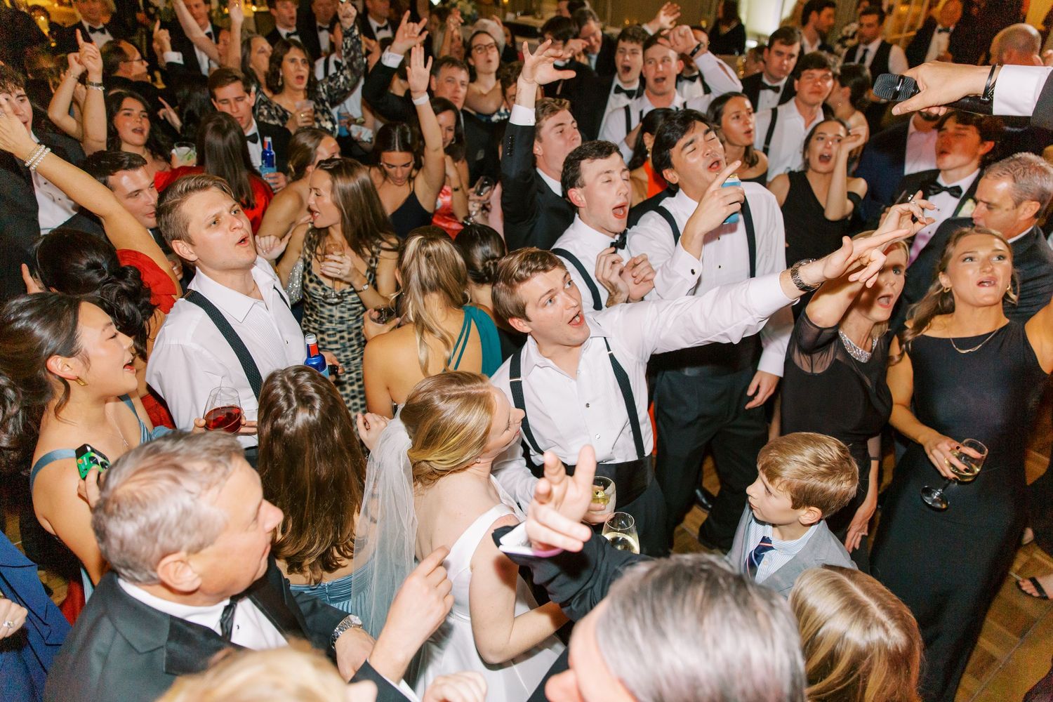 Energetic dance floor scene at a wedding reception with guests celebrating.
