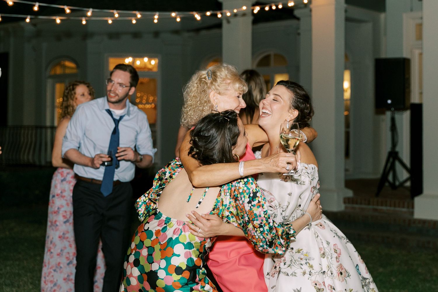 Wedding reception guests dancing under stringed lights in the evening.