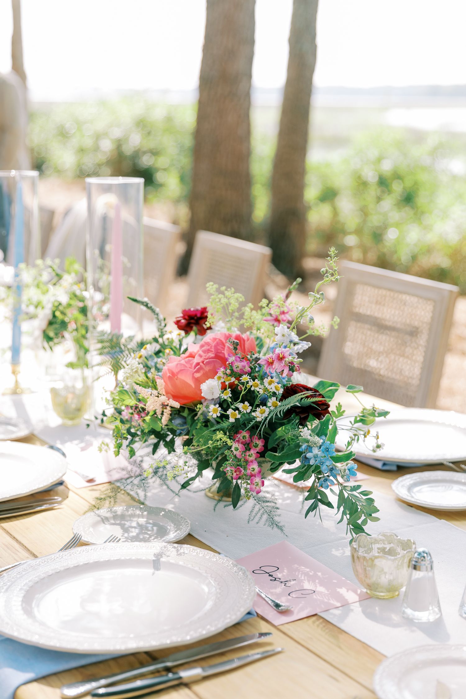 Elegant table setting with pink and blue floral centerpieces and white plates.