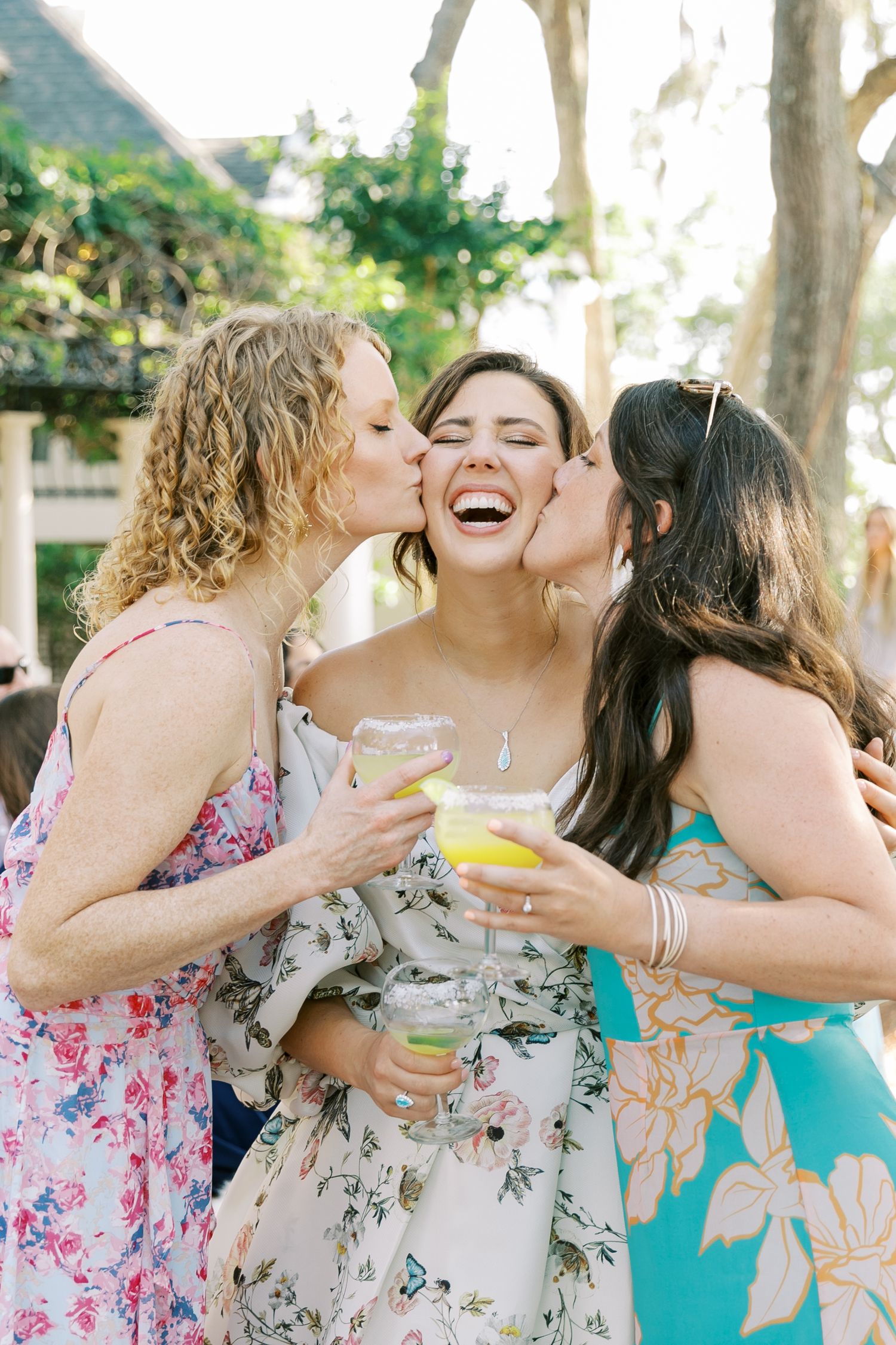 Three friends share a joyful moment celebrating with drinks at an outdoor event.