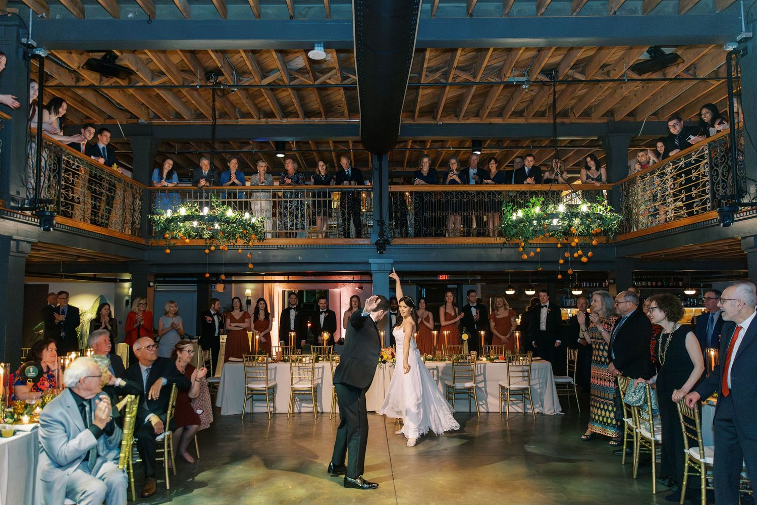 A reception venue with rustic wooden beams and balcony filled with wedding guests at Victory North in Savannah, GA.