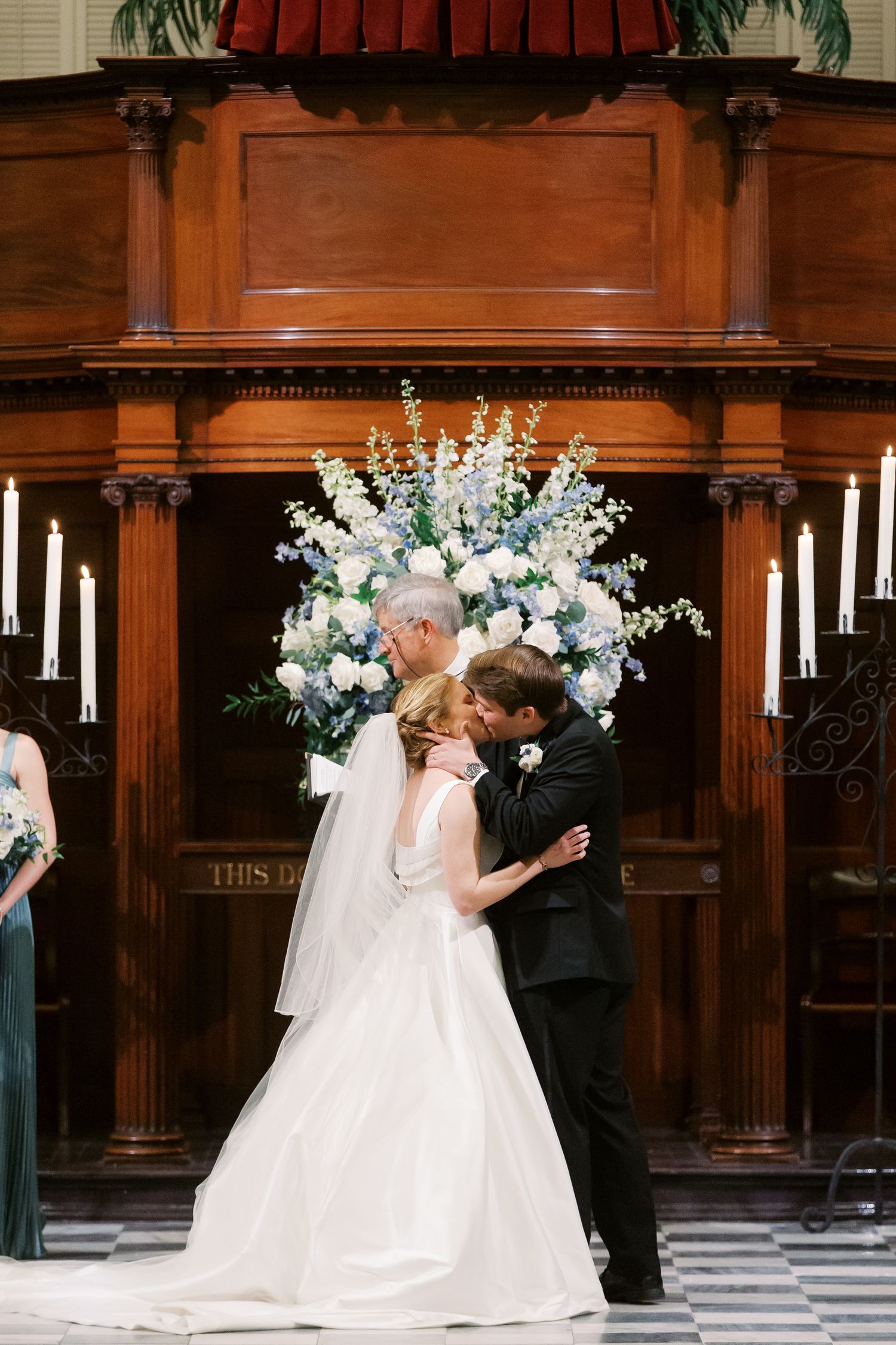 A romantic church wedding ceremony with white floral arrangements and wooden paneled walls.