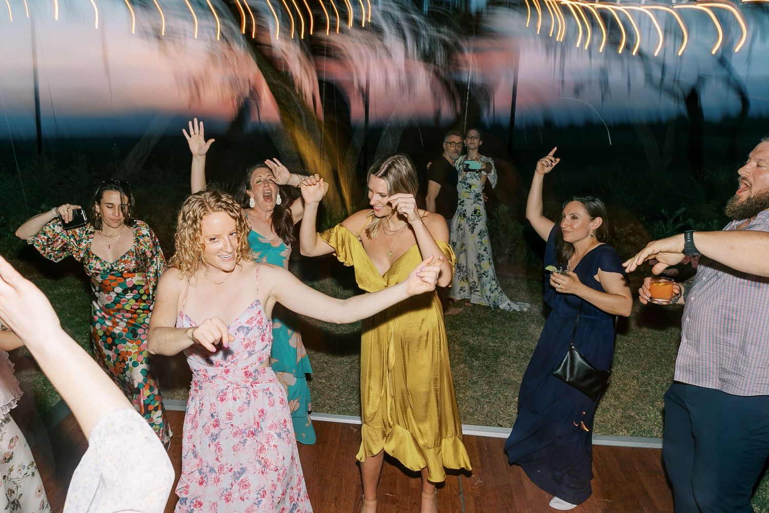 Guests dancing and celebrating at an outdoor evening reception under string lights.