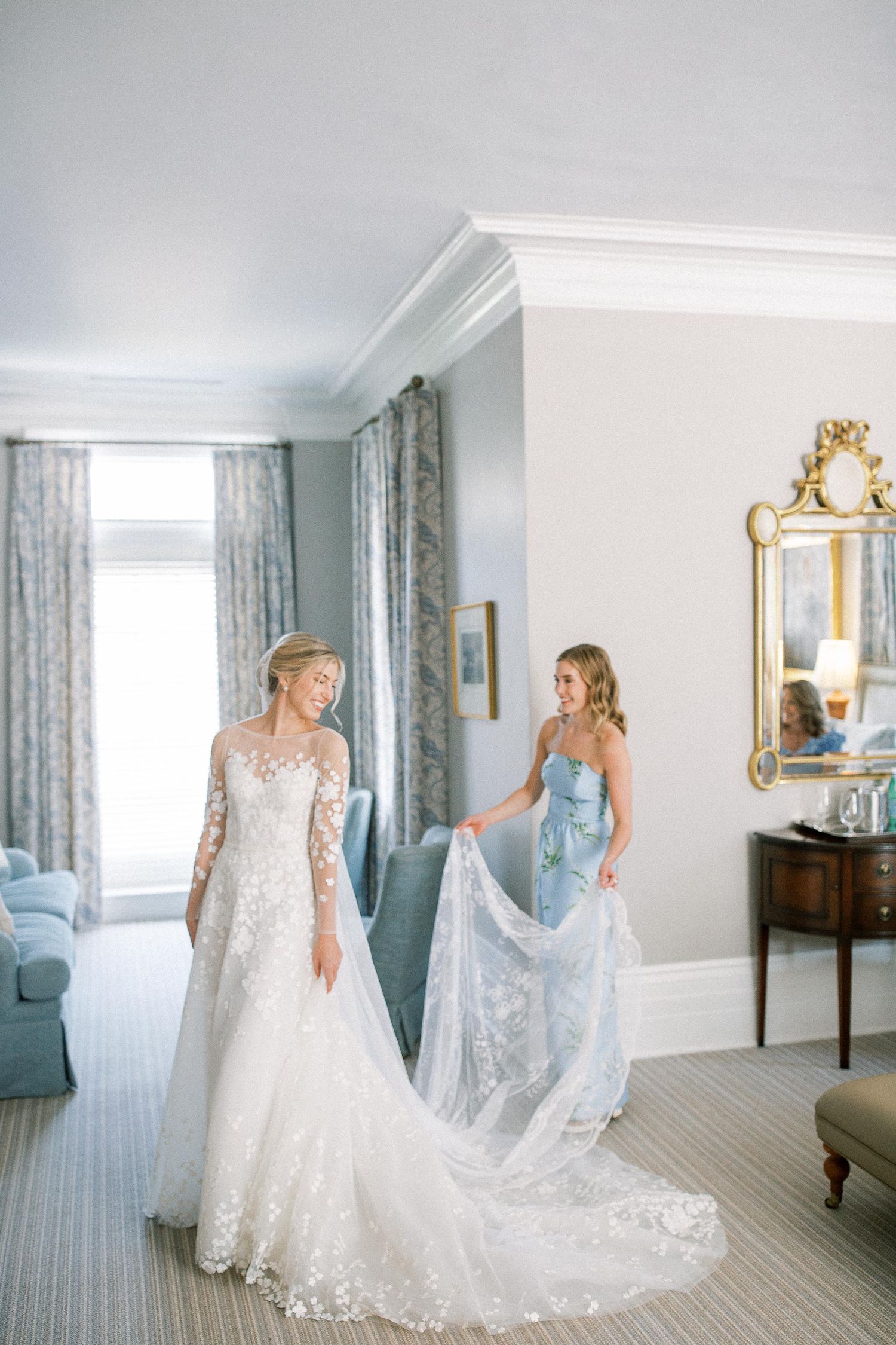 Elegant bridal preparations in a luxurious hotel room with blue and white decor and ornate gold mirrors.
