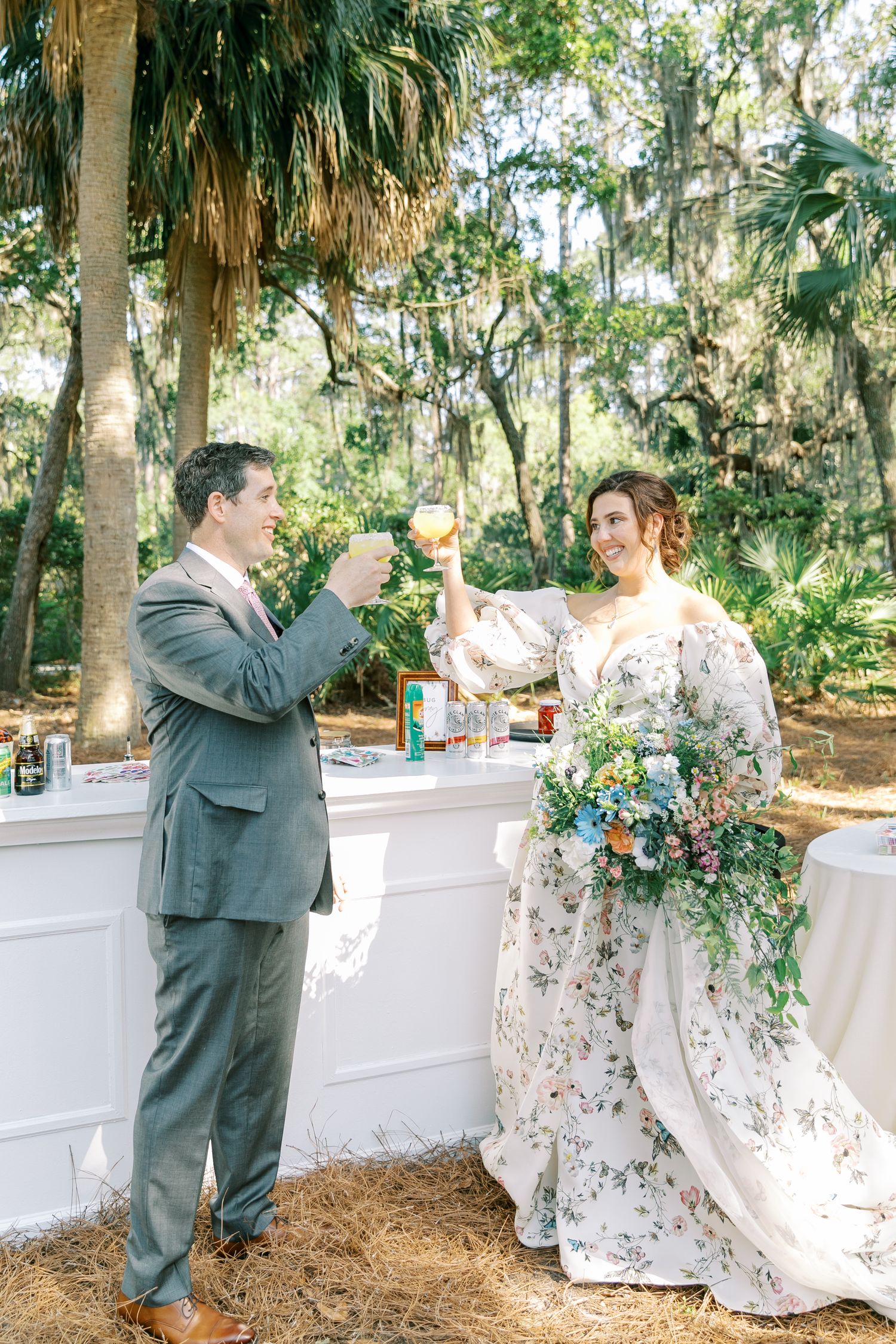 A couple shares a celebratory toast at an outdoor bar during their wedding.