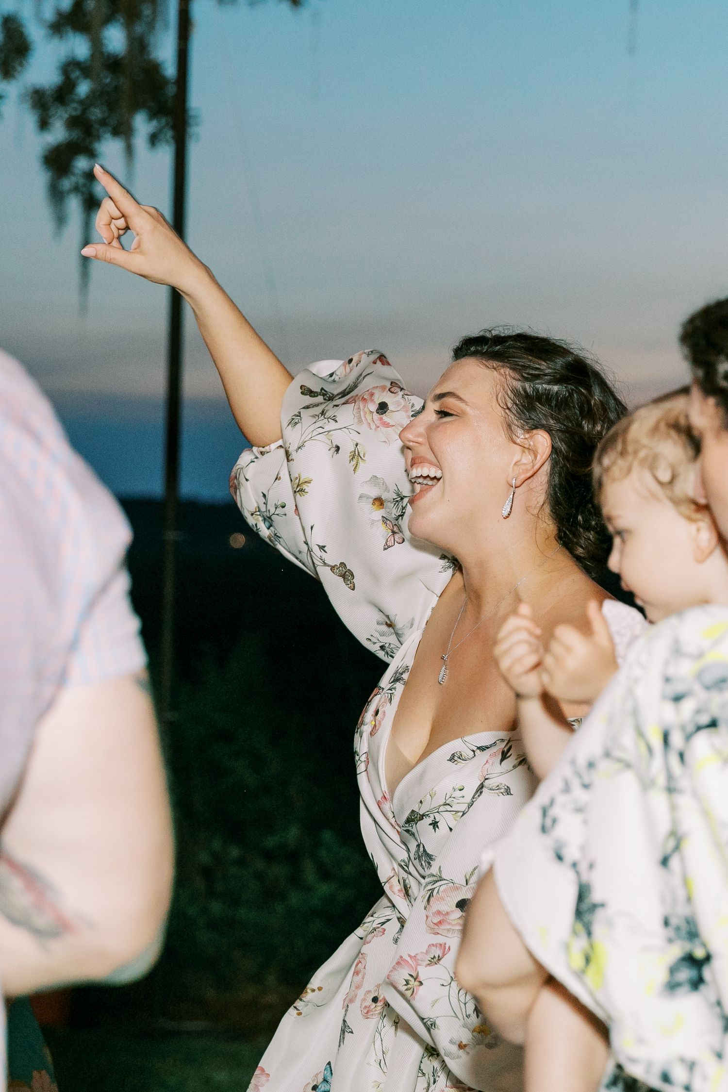Group celebrating outdoors in floral robes against an evening sky backdrop.