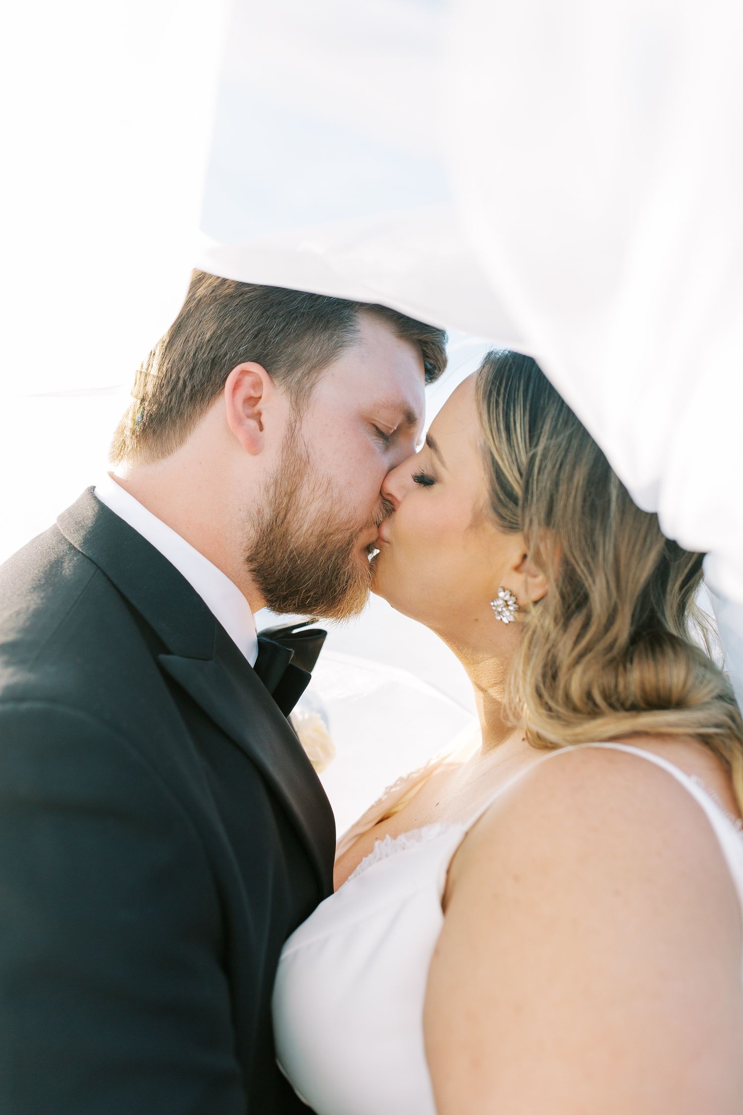A romantic wedding kiss with the couple sharing a tender moment together under soft lighting.