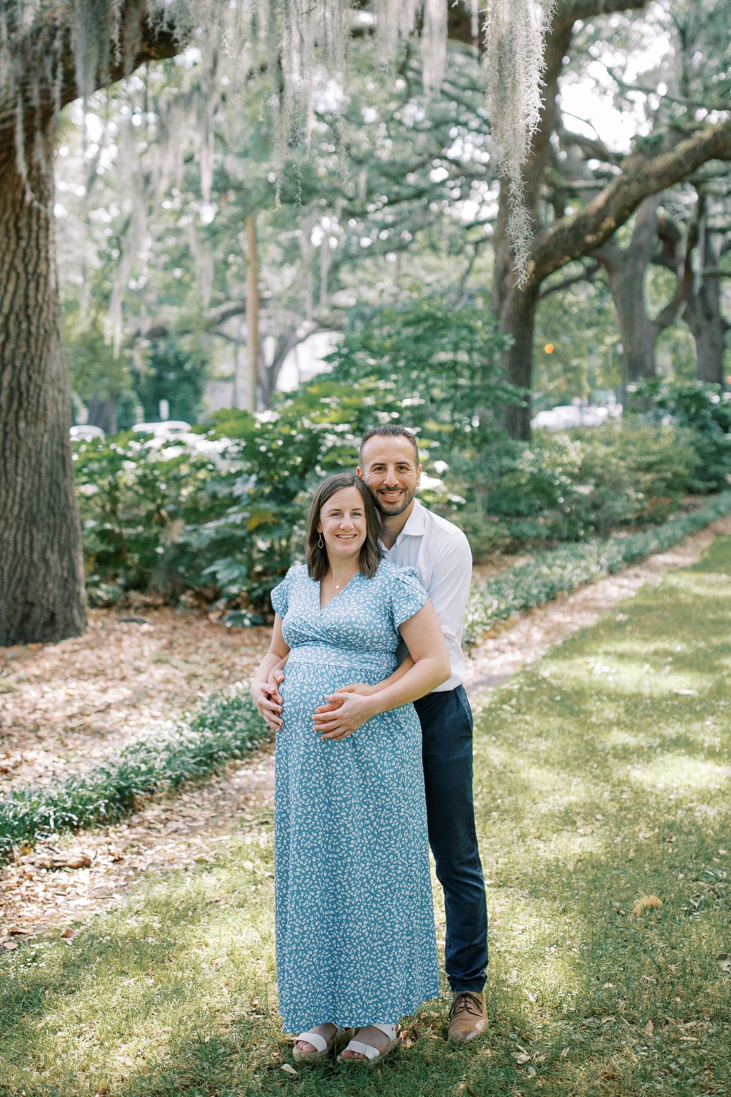 A tender moment captured between a couple under Spanish moss draped trees in a park.
