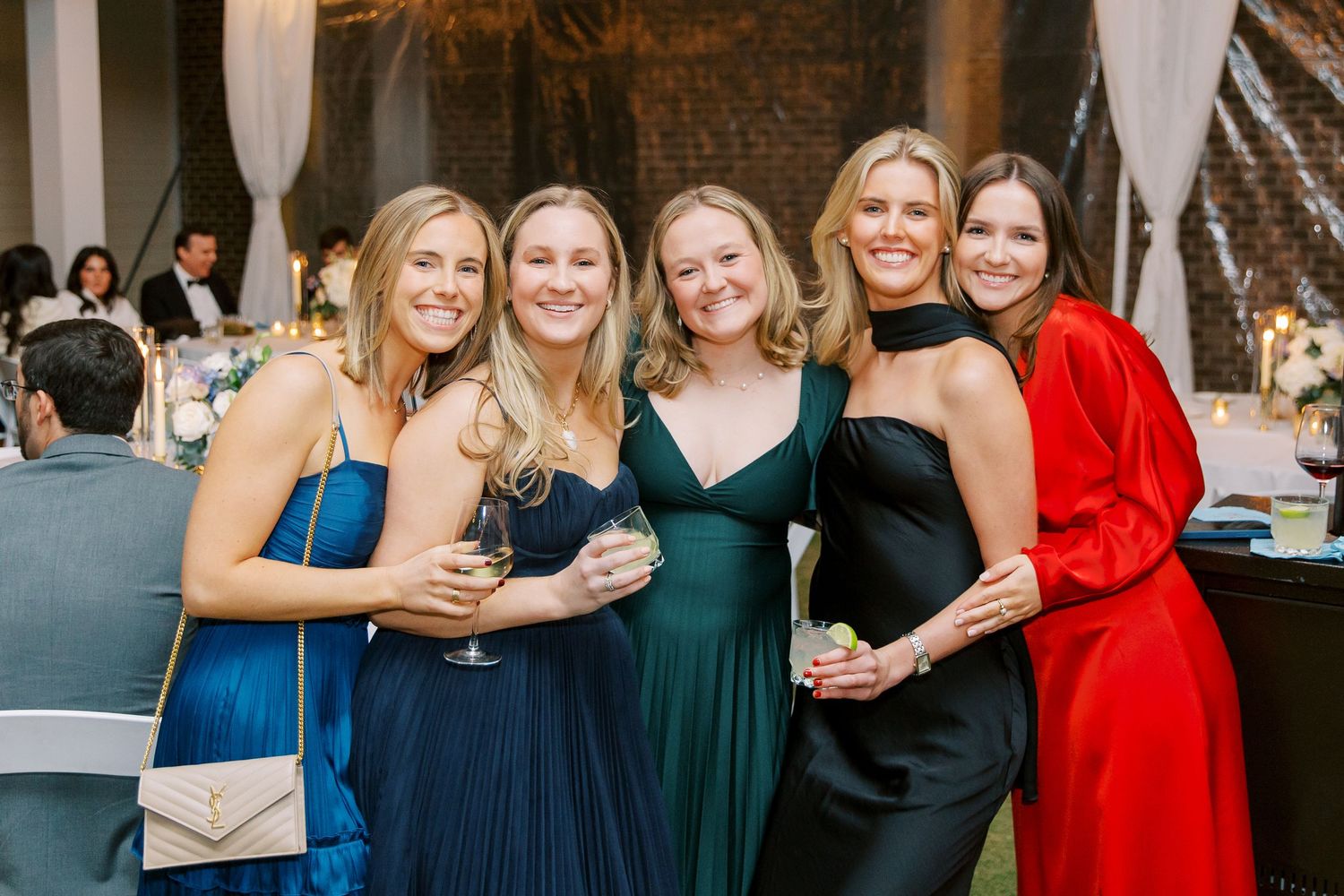 Group of wedding guests in formal attire gathered at an evening reception.