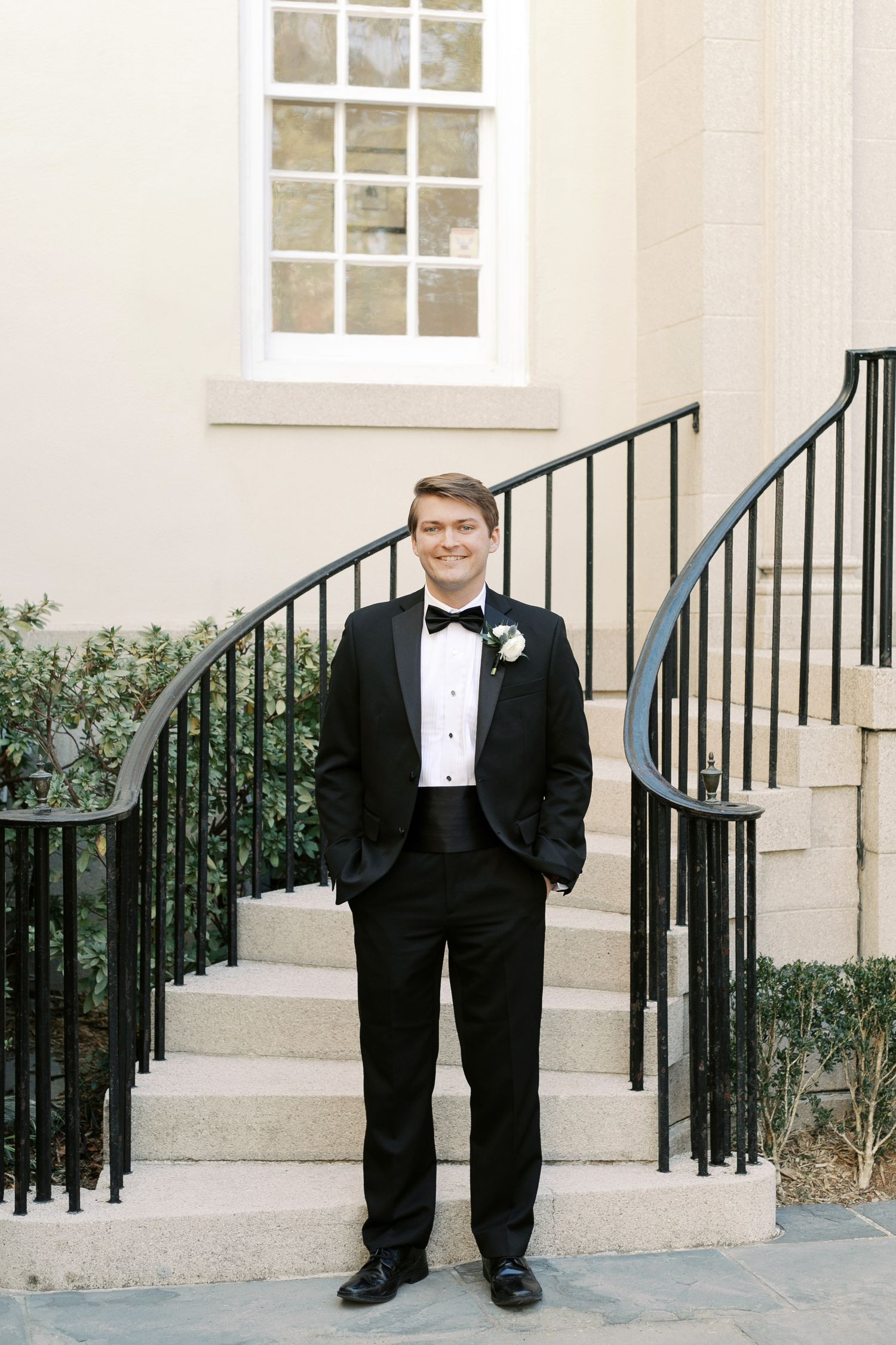 Classic black tuxedo formal wedding attire photographed against light colored building exterior.