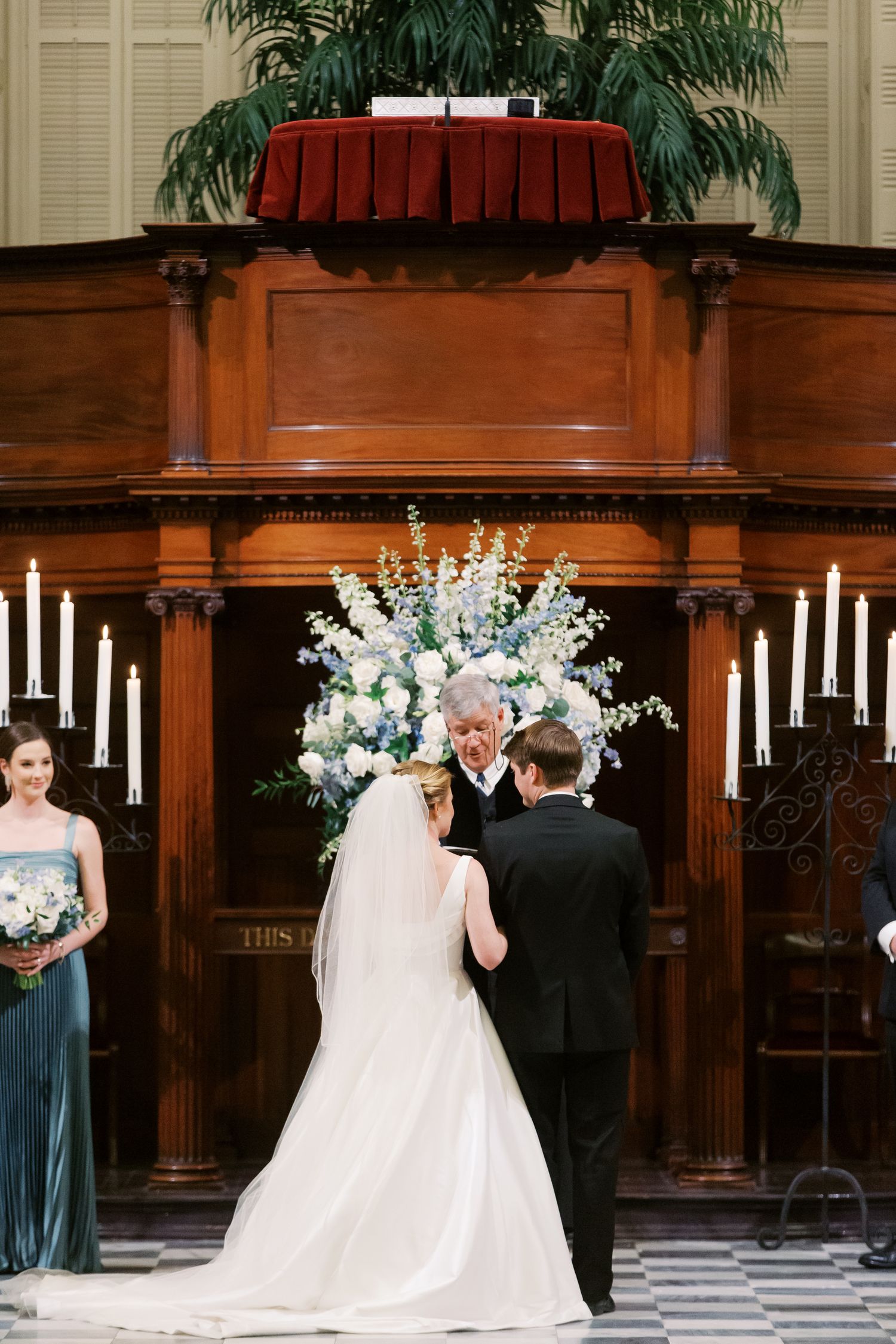 Traditional church wedding ceremony with floral arrangements and candles at a wooden altar.
