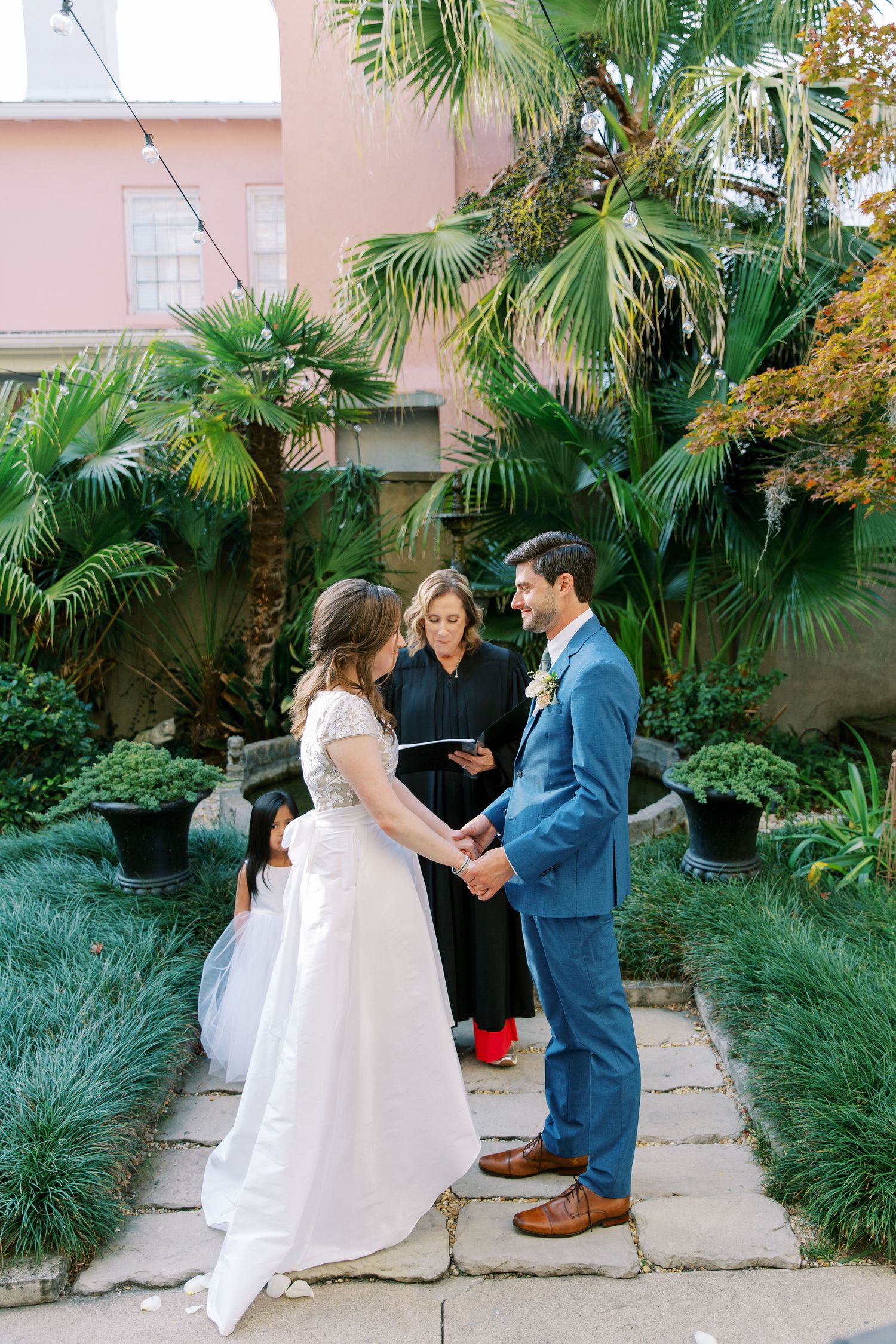 An outdoor wedding ceremony in a tropical garden setting with palm trees.