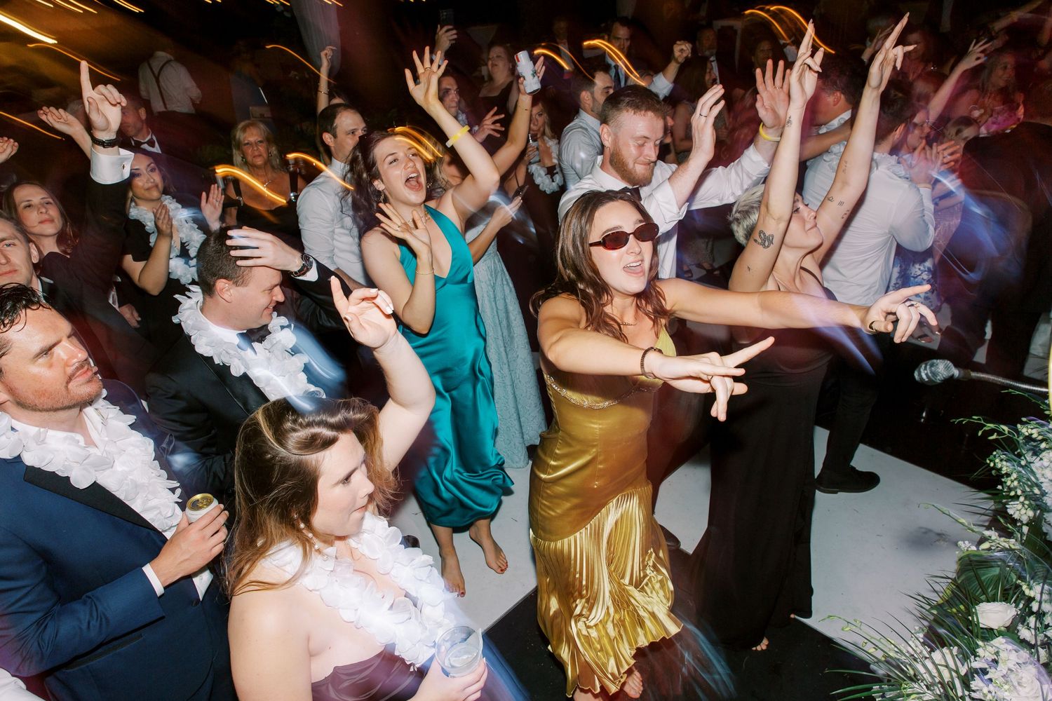 Energetic wedding reception dance party with guests celebrating on crowded dance floor.