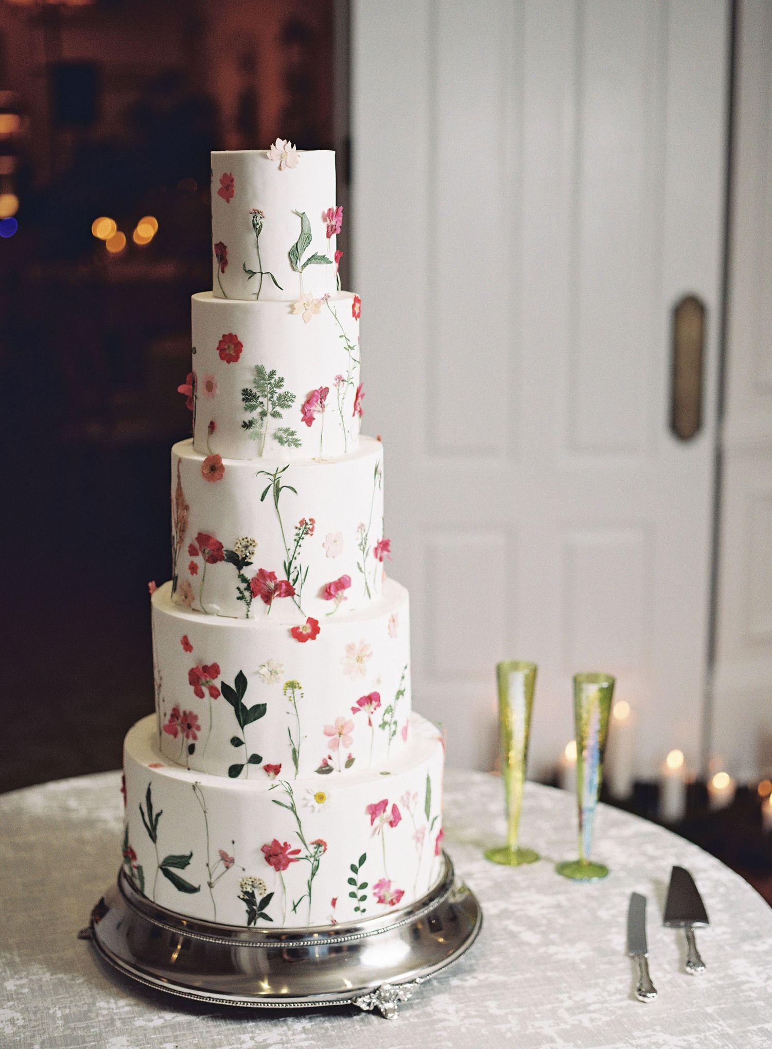 Five-tier white wedding cake decorated with delicate hand-painted floral designs.