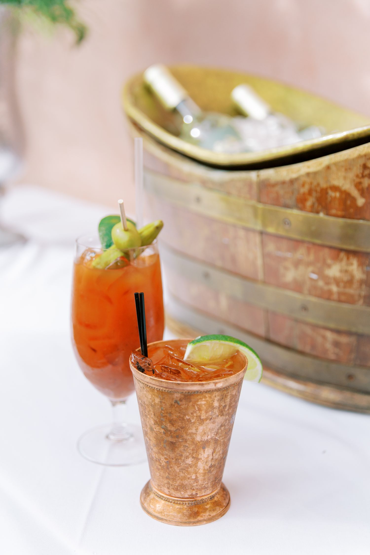 Two craft cocktails garnished with lime and herbs on an elegant table setting.