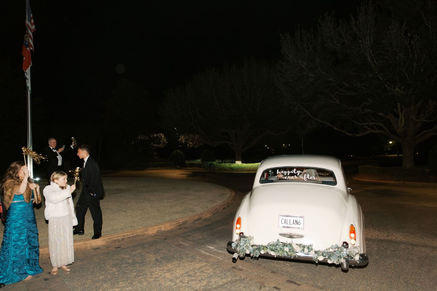 Vintage white getaway car parked outside venue at night.