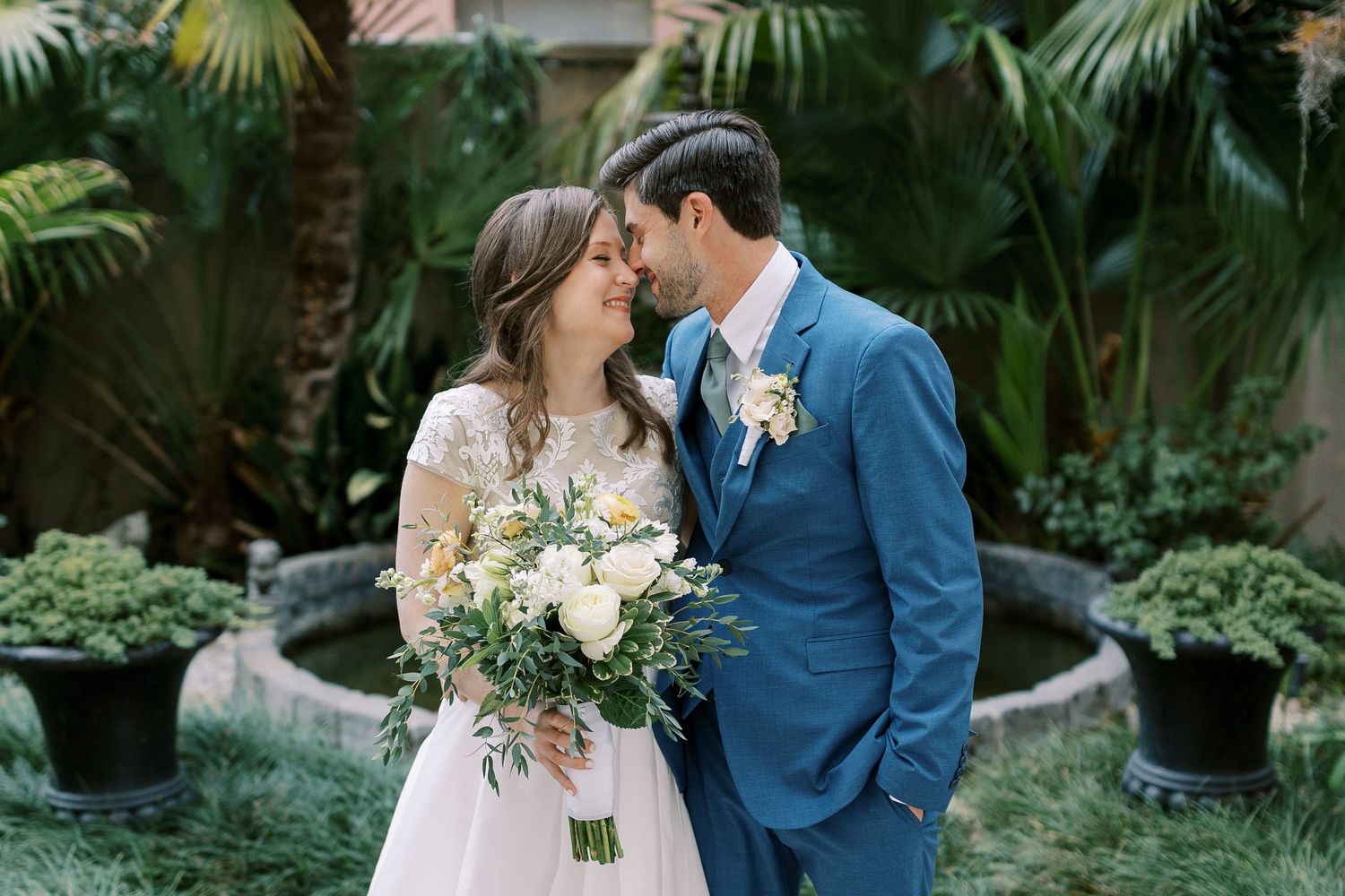 An intimate garden wedding moment surrounded by lush tropical plants and greenery.
