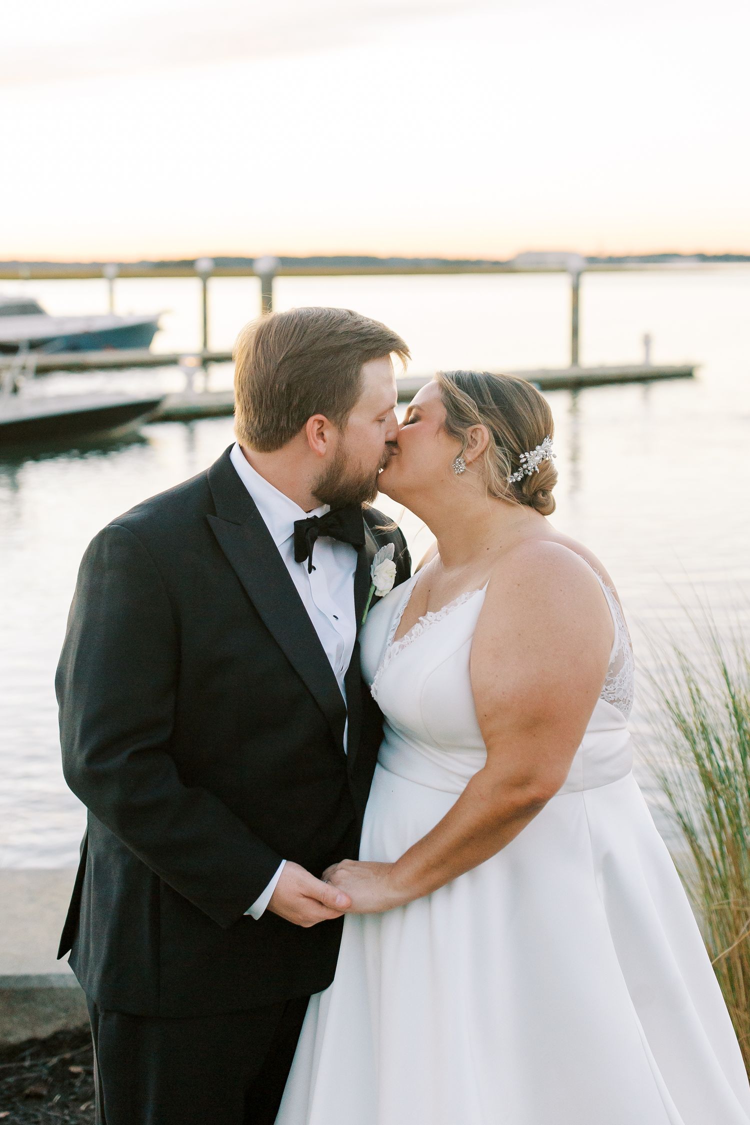 A tender moment between newlyweds by a marina at sunset.