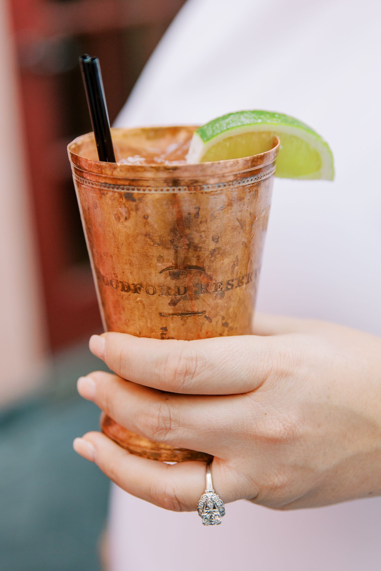 A copper Moscow Mule cocktail in a metal cup garnished with a lime wedge and black straw.