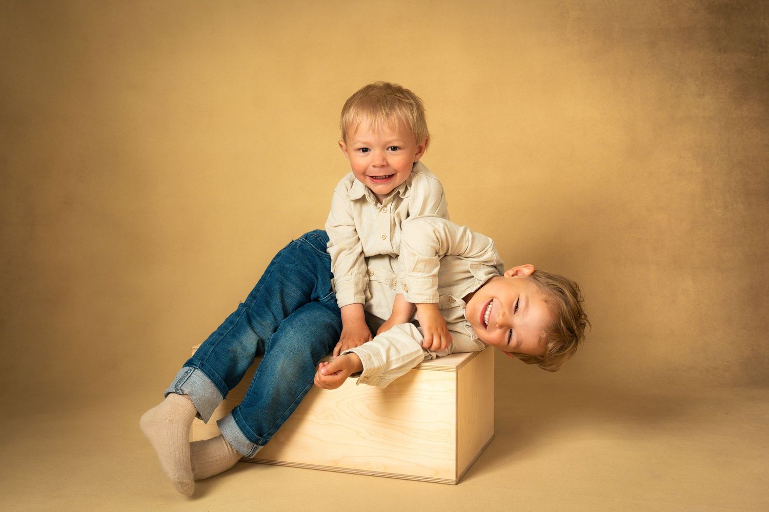 Syskon busar med varandra och skrattar under familjefotografering i studio.