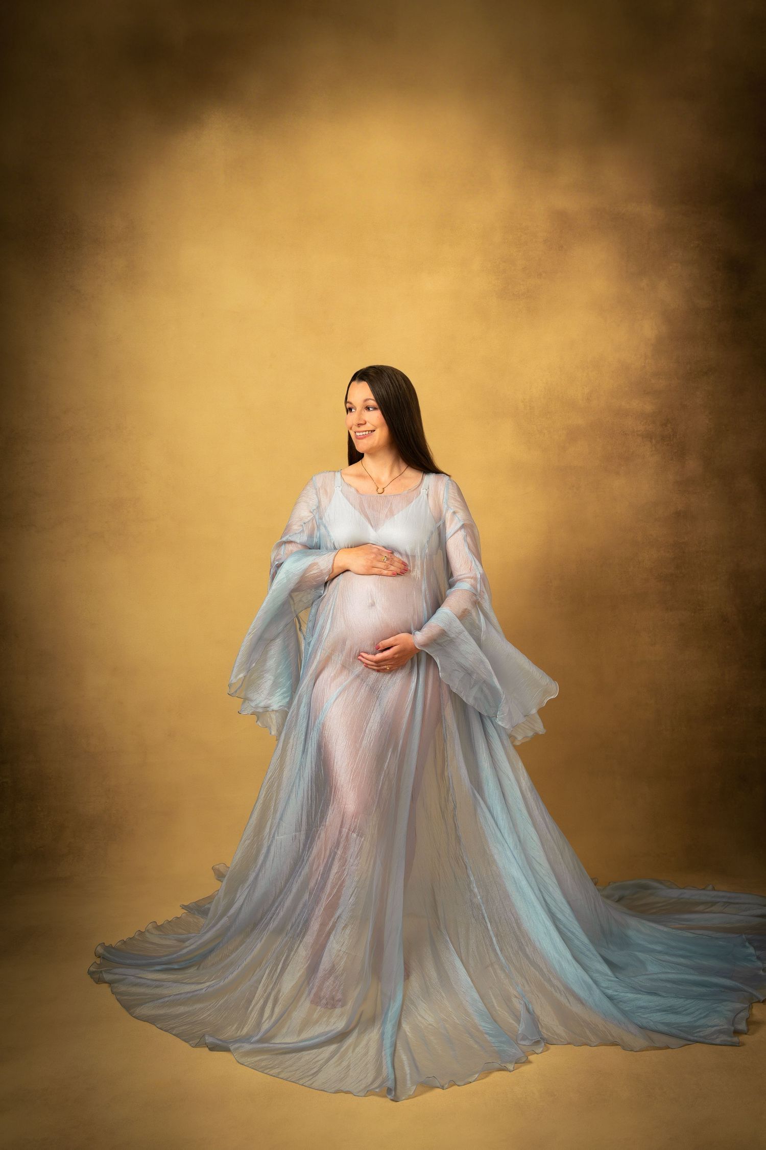 Elegant gravidfotografering – mamma poserar med vacker blå klänning i studion.