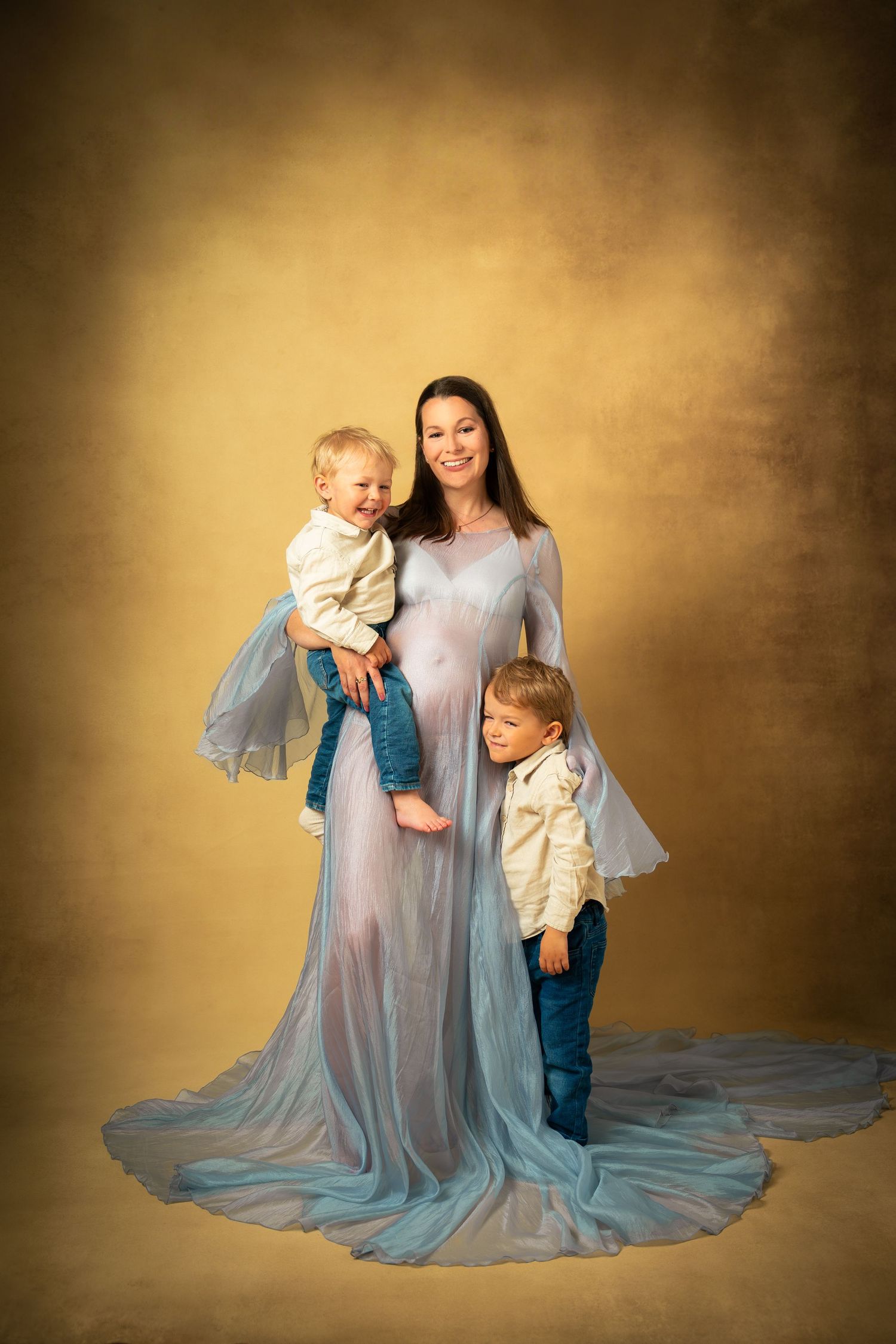 Kärleksfull gravidfotografering – mamma skrattar med sina barn i studion.