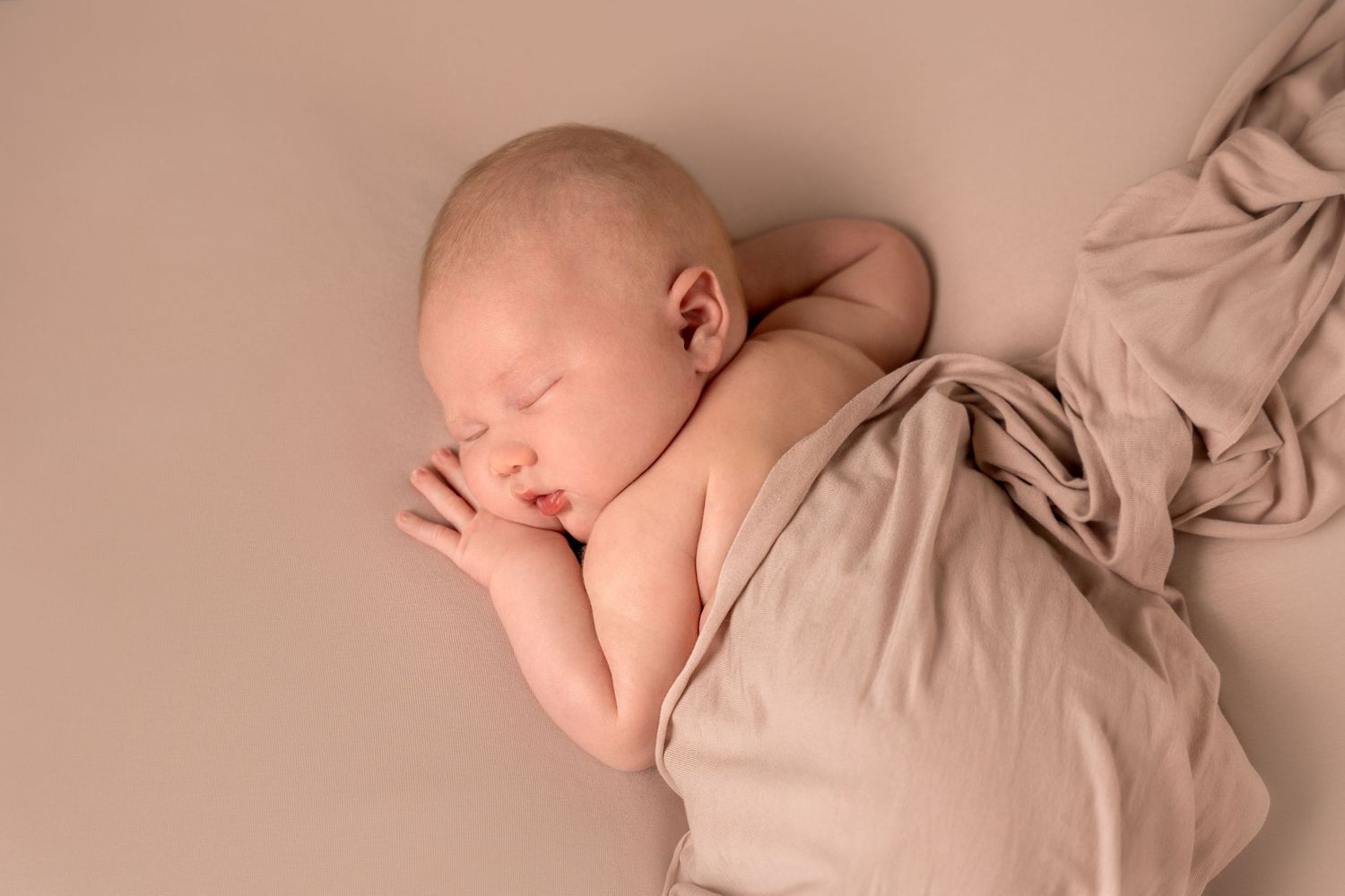 Nyföddfotografering i Göteborg – sovande bebis i rosa tyg i studio.