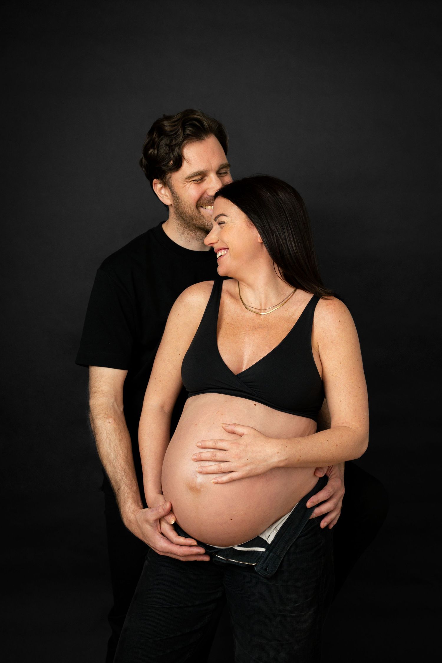 Par skrattar tillsammans under gravidfotografering i Göteborg.