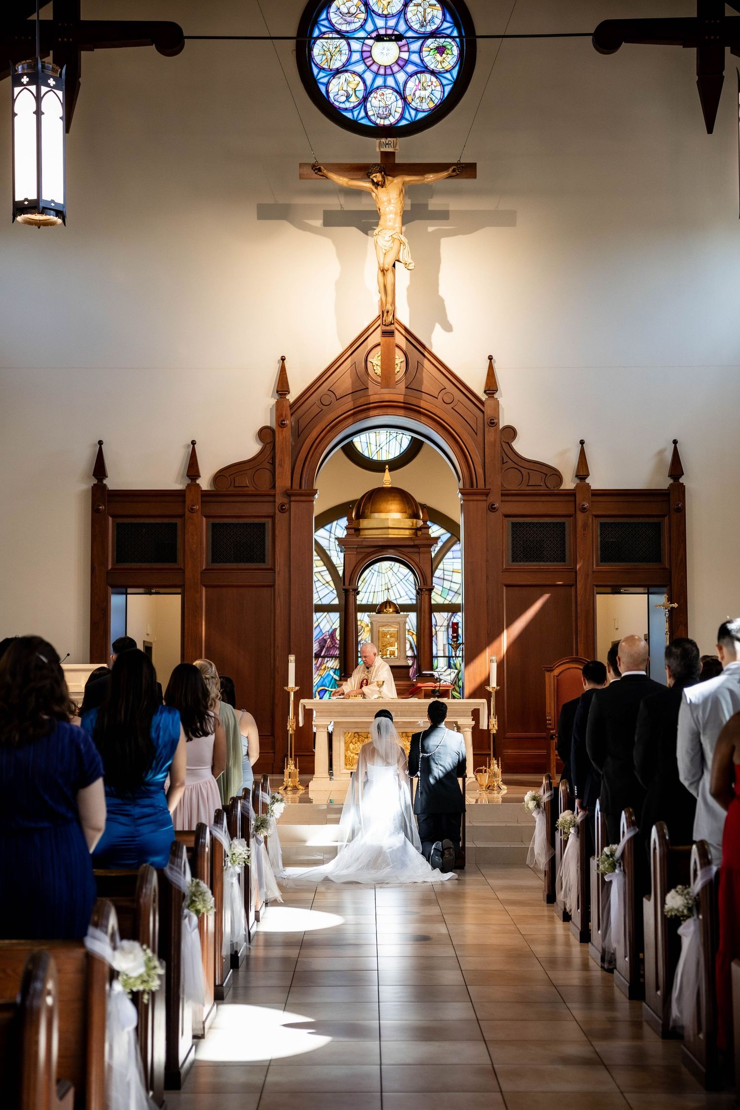 Bride and groom kneeling at the altar during a Catholic wedding ceremony inside a beautiful church.