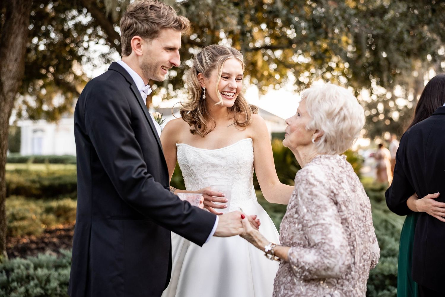 Candid outdoor wedding celebration moments captured in golden sunlight with guests enjoying the festivities.