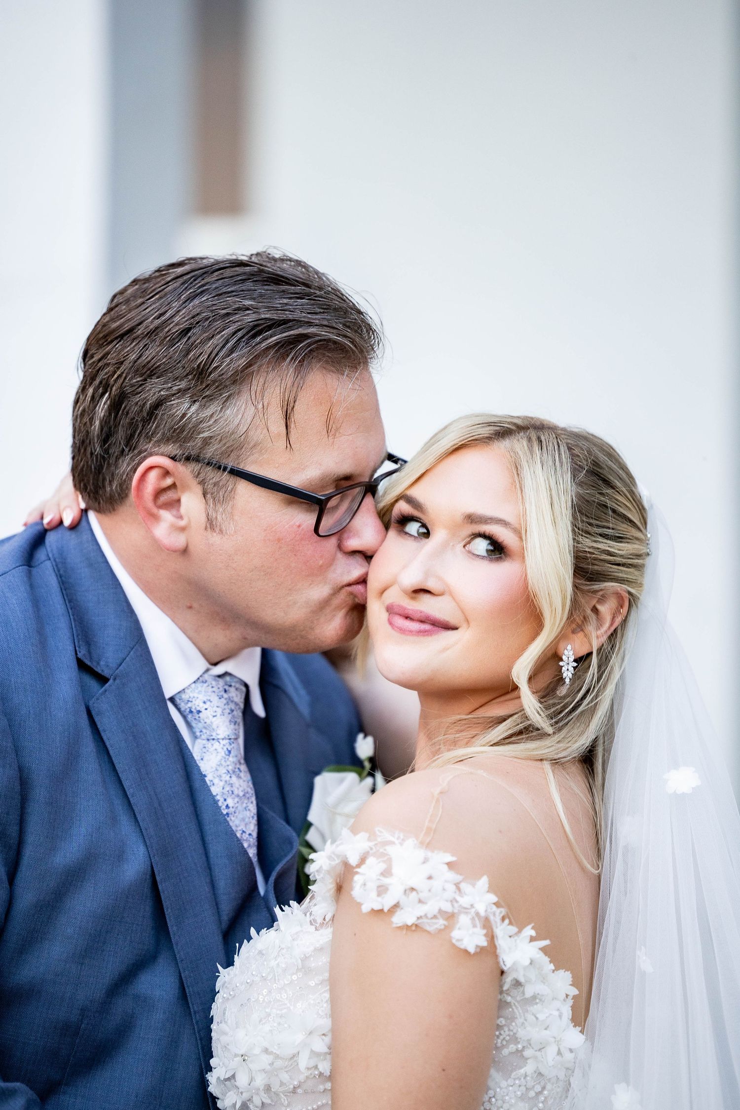 A romantic wedding portrait showing a tender moment between newlyweds in formal attire.