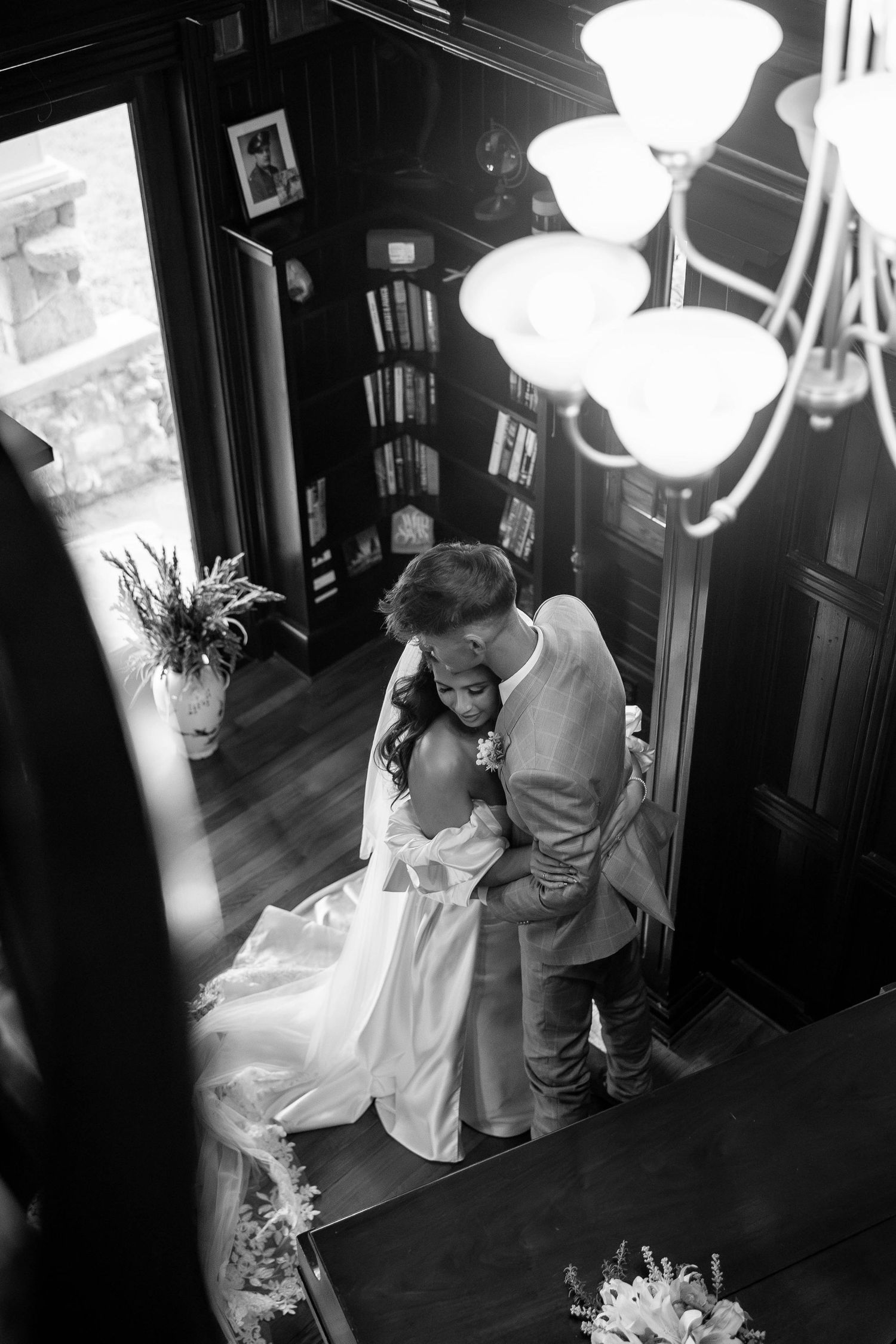 A dramatic black and white photo series showing a couple dancing intimately in a dimly lit room with hanging lights.