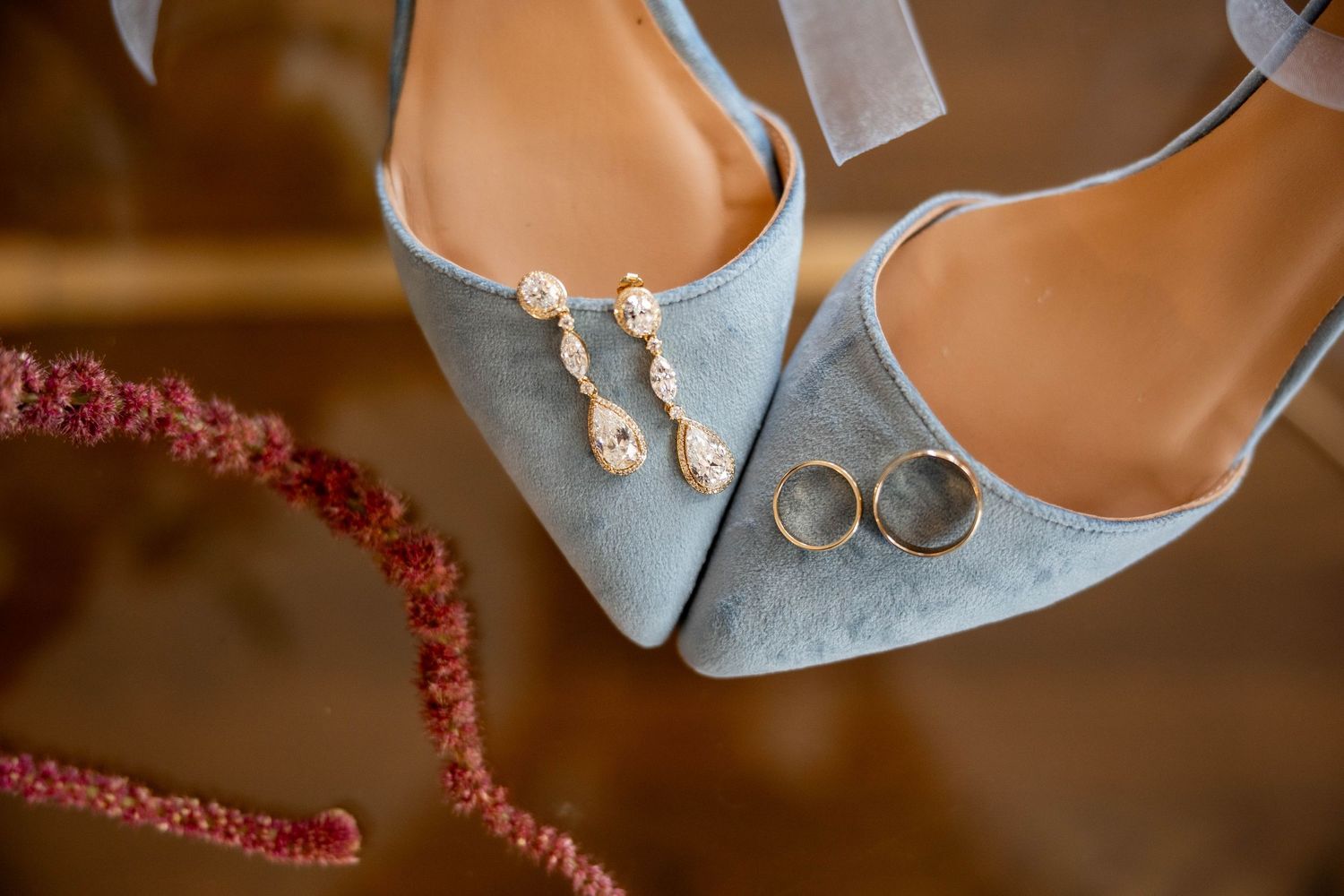 Wedding shoes and accessories arranged artistically on a rustic wooden surface with soft lighting.