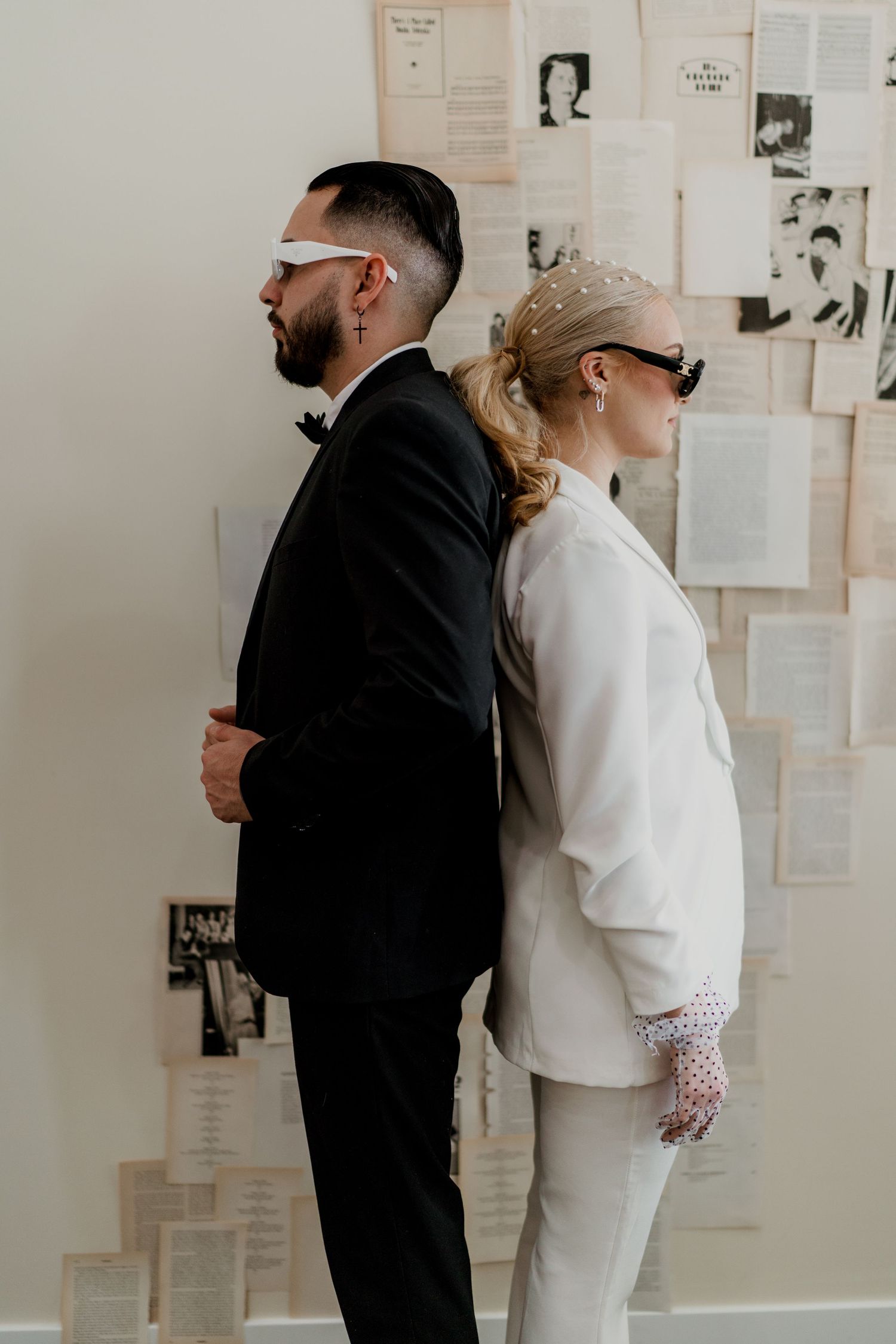 Bride and groom standing back to back wearing sunglasses and blindfold.