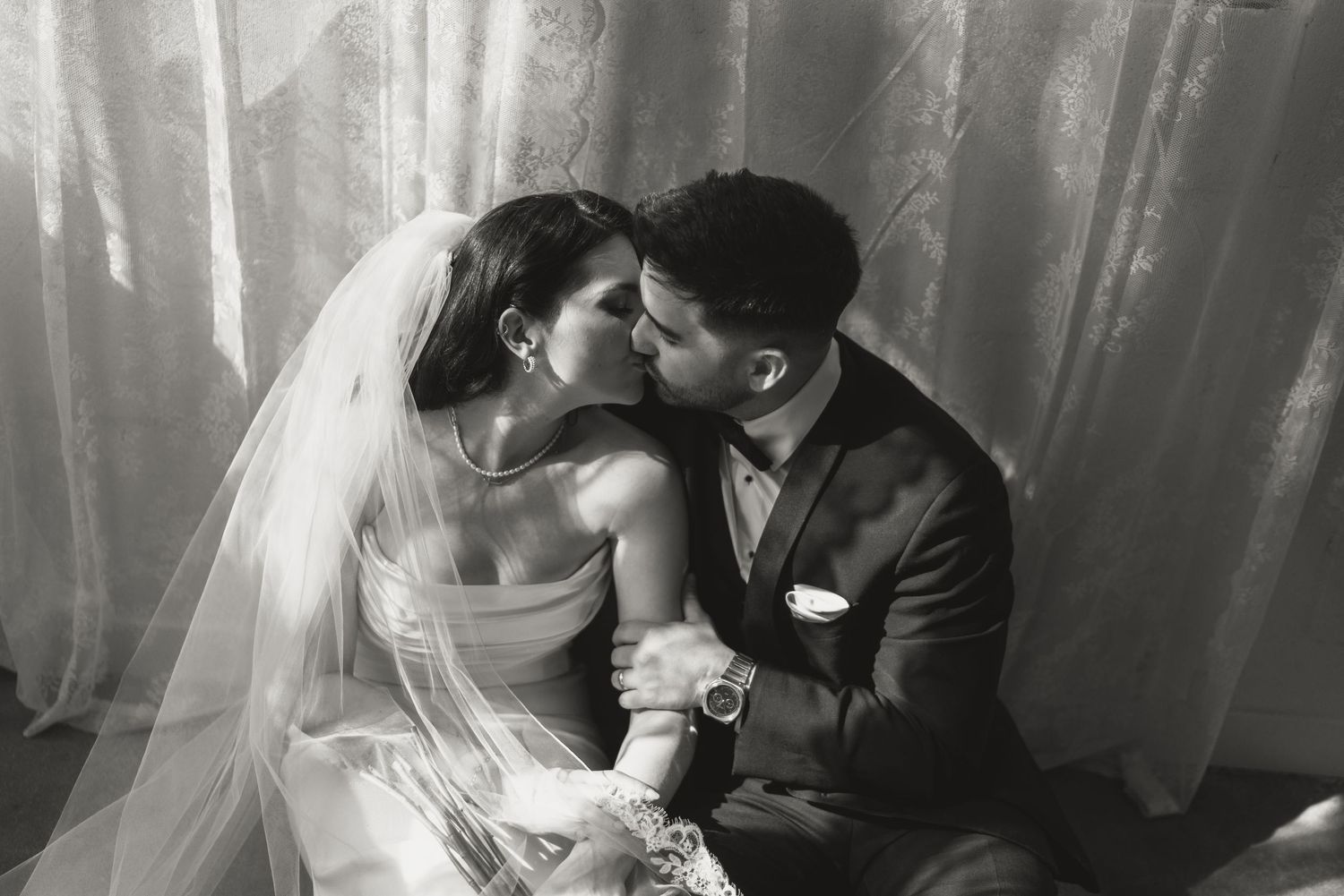 Black and white photo of bride and groom sharing a romantic kiss on their wedding day.