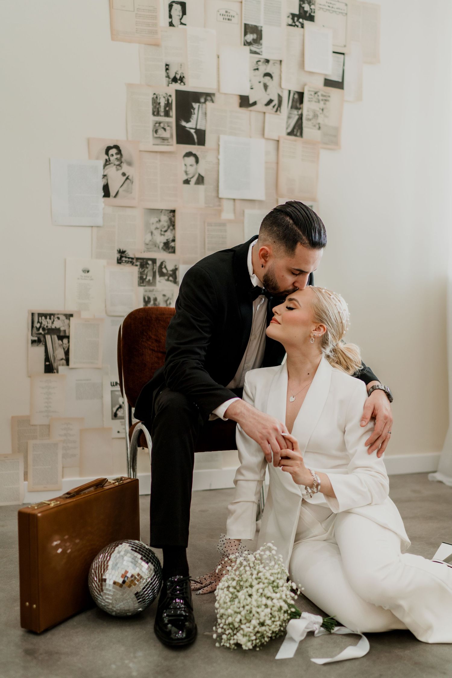 Couple in wedding attire sharing a tender moment with vintage backdrop.