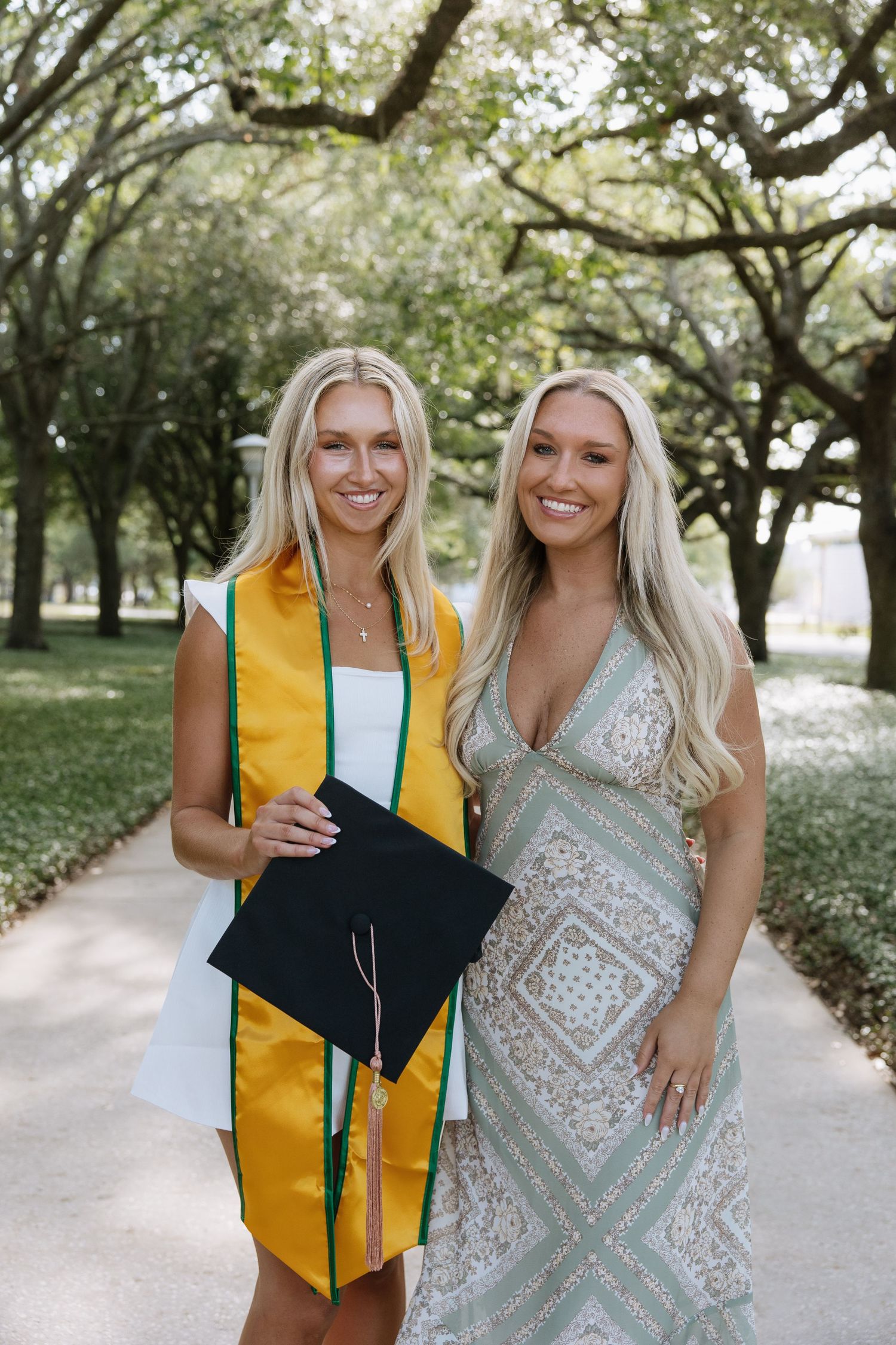 A University of South Florida grad stands with her sister captured by Tampa grad photographer Michaela Gom Photography.
