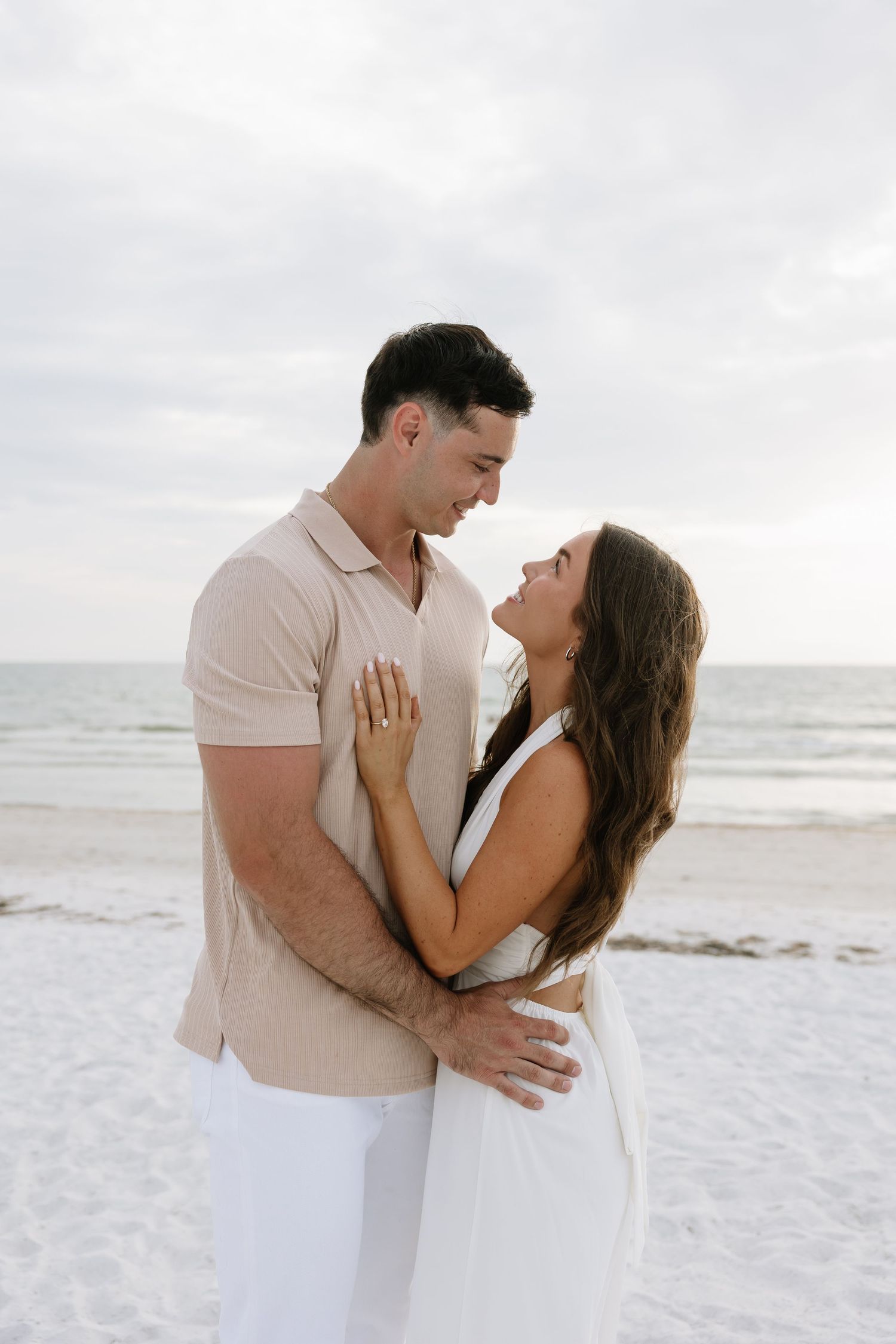 Engaged couple stands looking at eachother. Captured by Michaela Gom Photography.