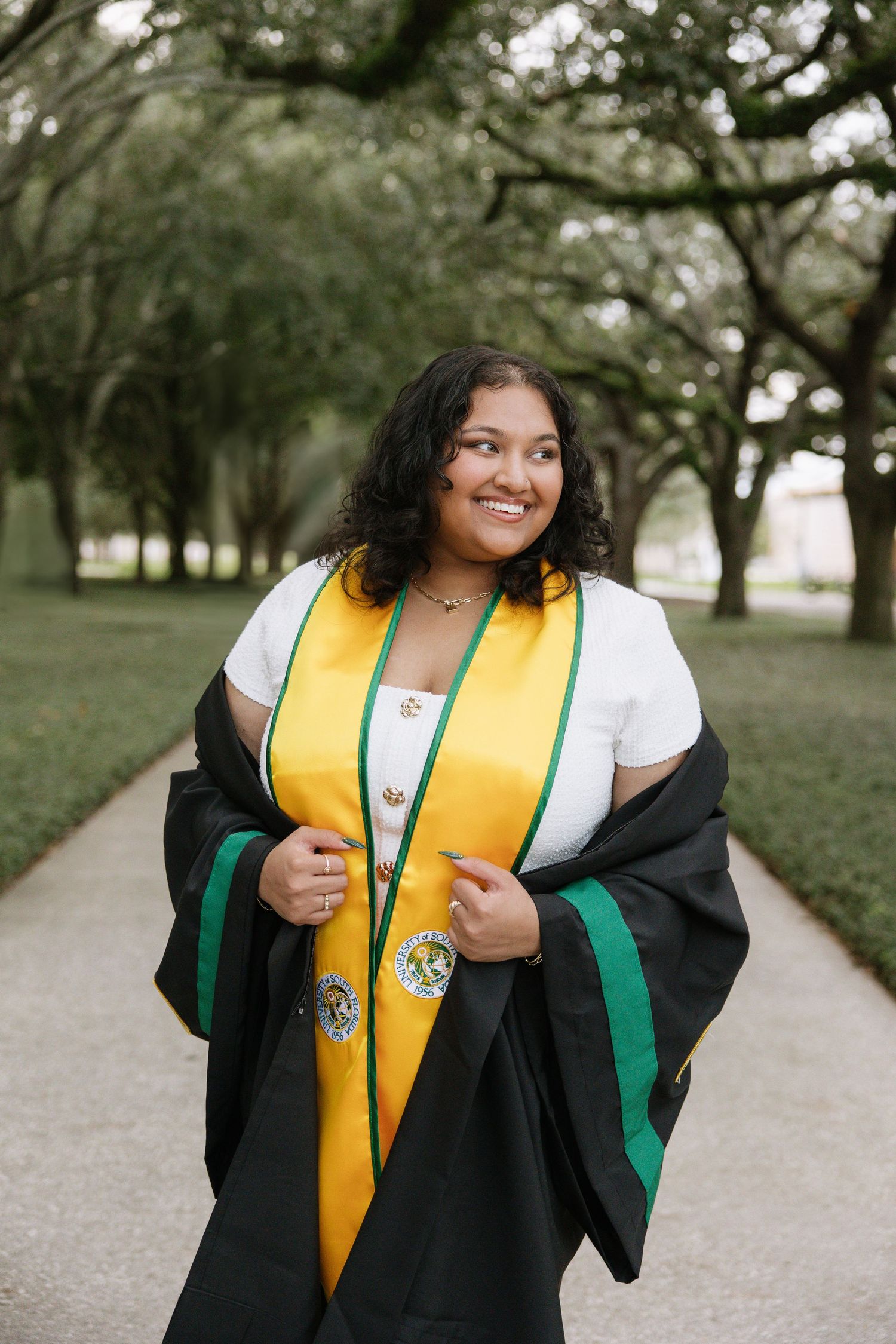 A USF Grad is smiling looking away taken by Tampa grad photographer Michaela Gom Photography.