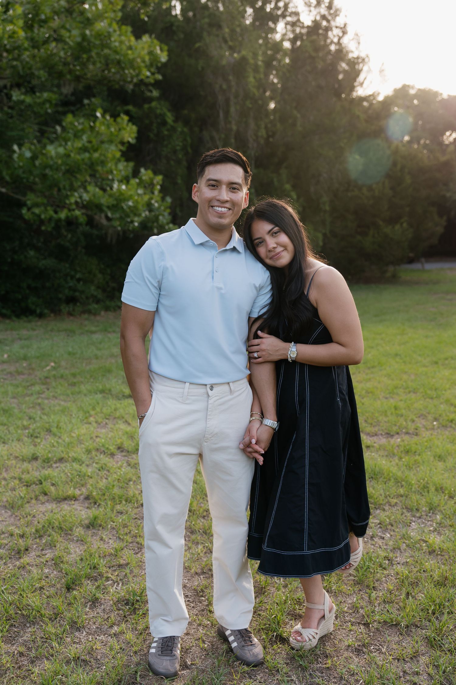 Engaged couple stands by eachother captured in a green park edited by timeless true to color photographer Michaela Gom Photography.