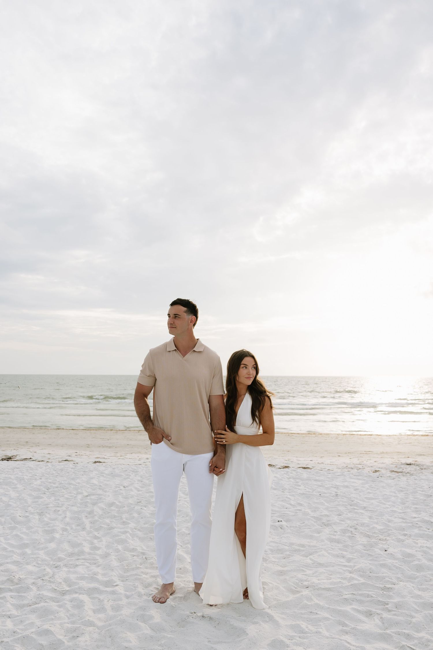 Engaged couple stands next to eachother while looking away. Editorial posing. Captured by Michaela Gom Photography.