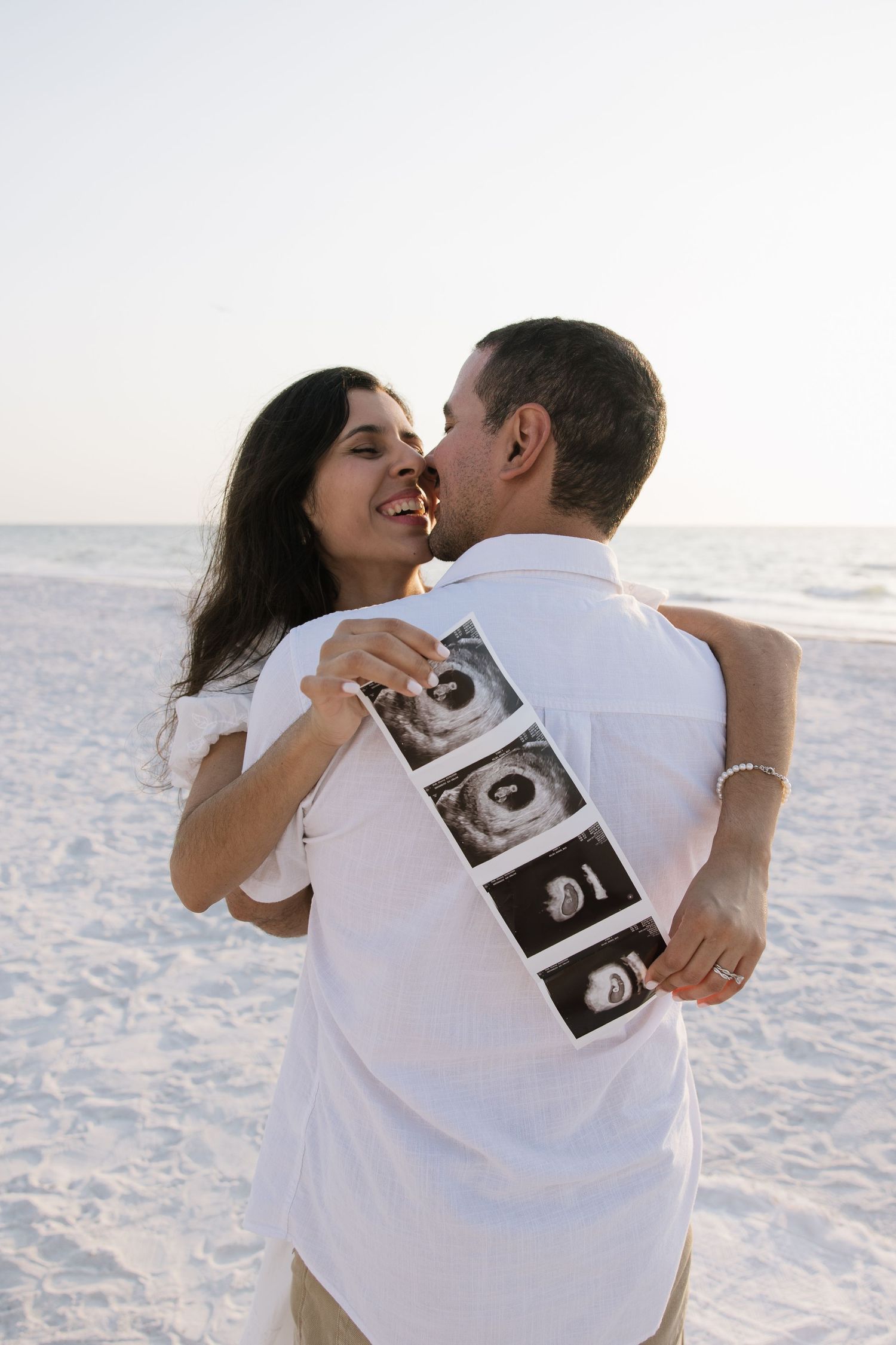 A couple is holding up their sonogram for a gender reveal for their maternity photos captured by Michaela Gom Photography.
