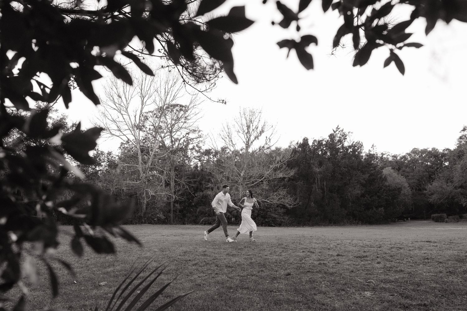 An engaged couple from Tampa are running together at Philippe park captured by Michaela Gom Photography.