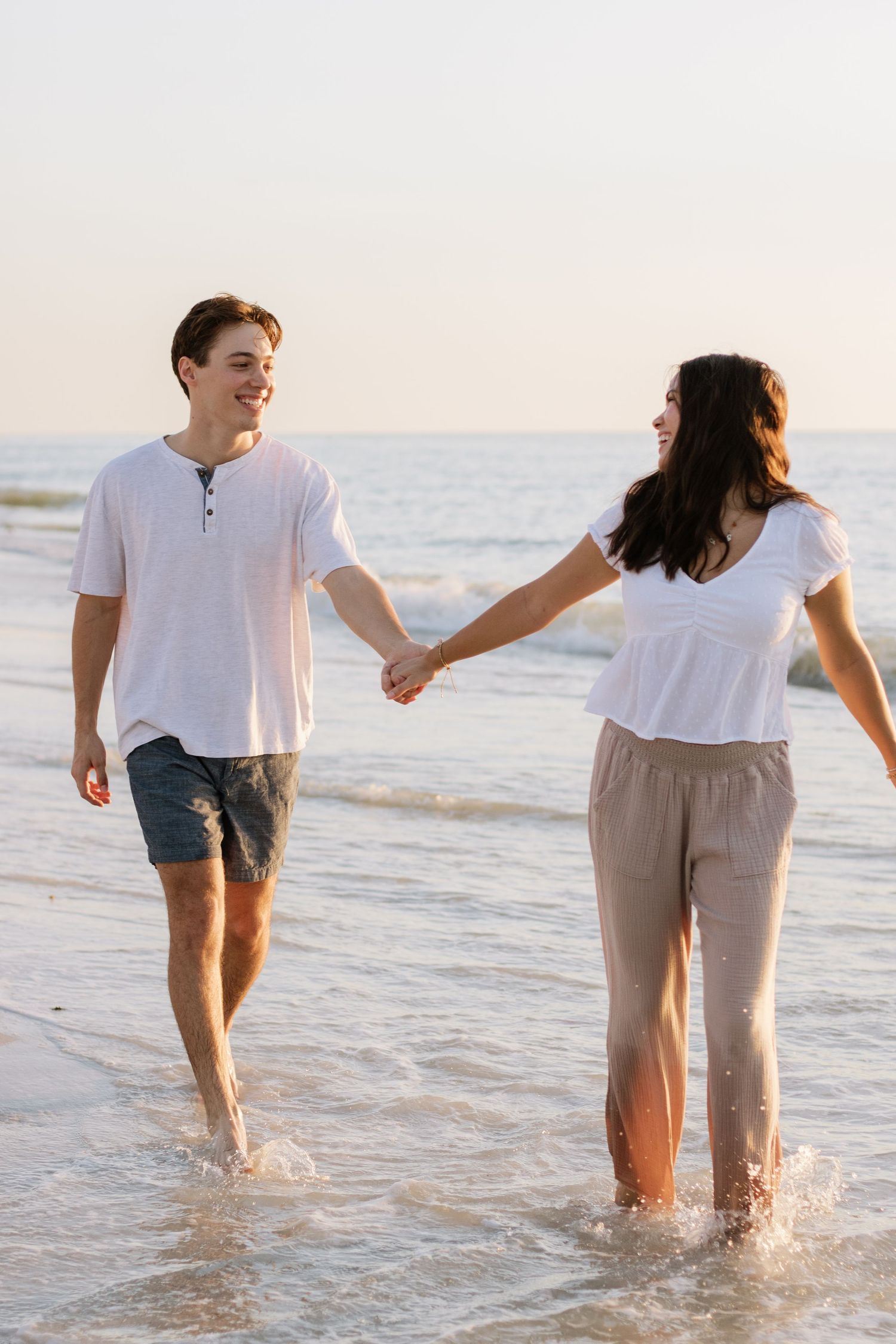 Young couple is walking alongside each other on Indian Rocks Beach, Florida captured by Tampa Photographer Michaela Gom Photography.