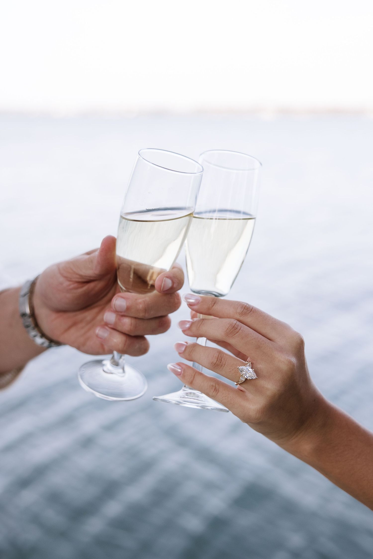 A couple cheers with champagne as they celebrate their recent engagement captured at Philippe Park by Michaela Gom Photography.