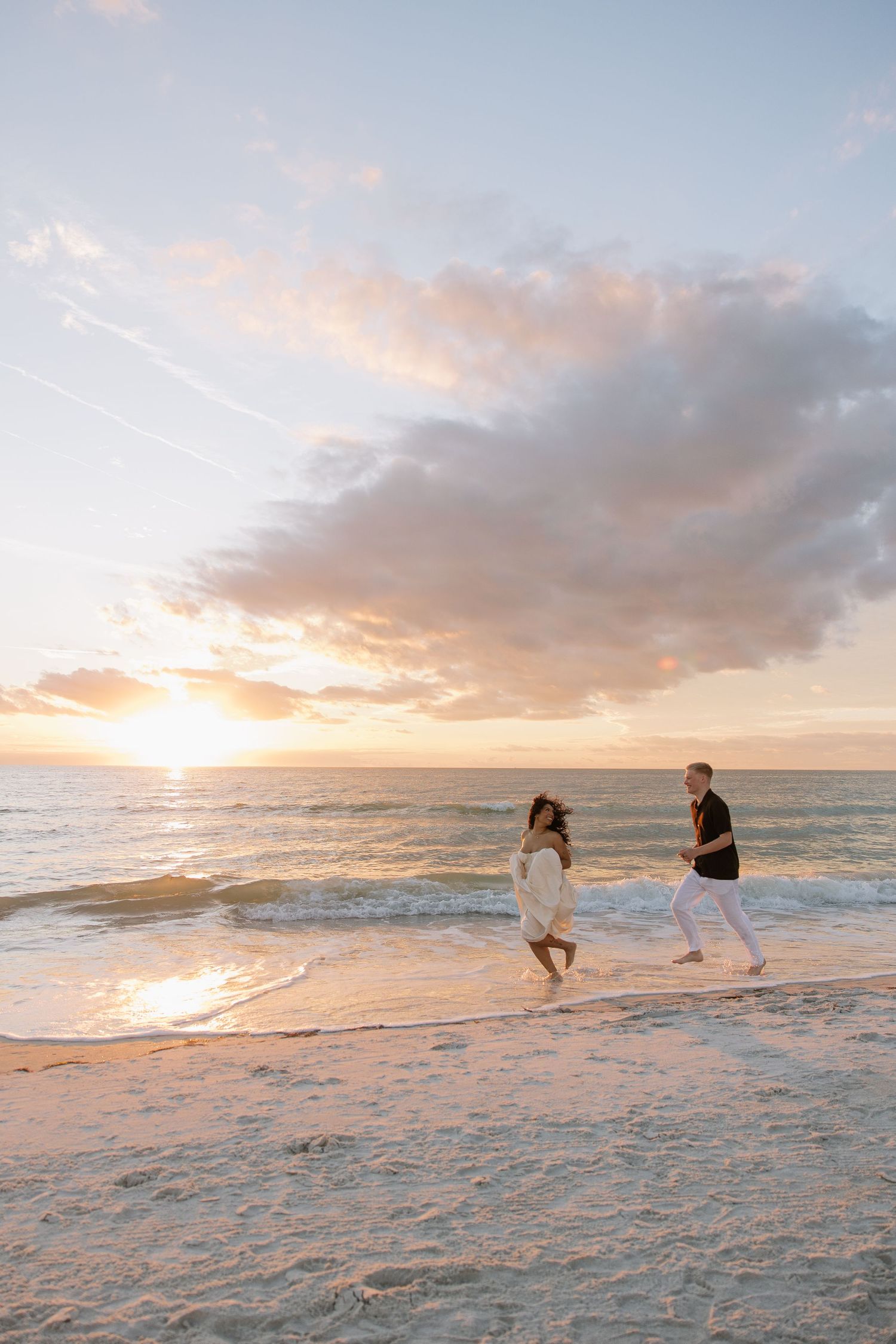 Engaged couple at Treasure Island Beach running along side eachother captured by Michaela Gom Photography.