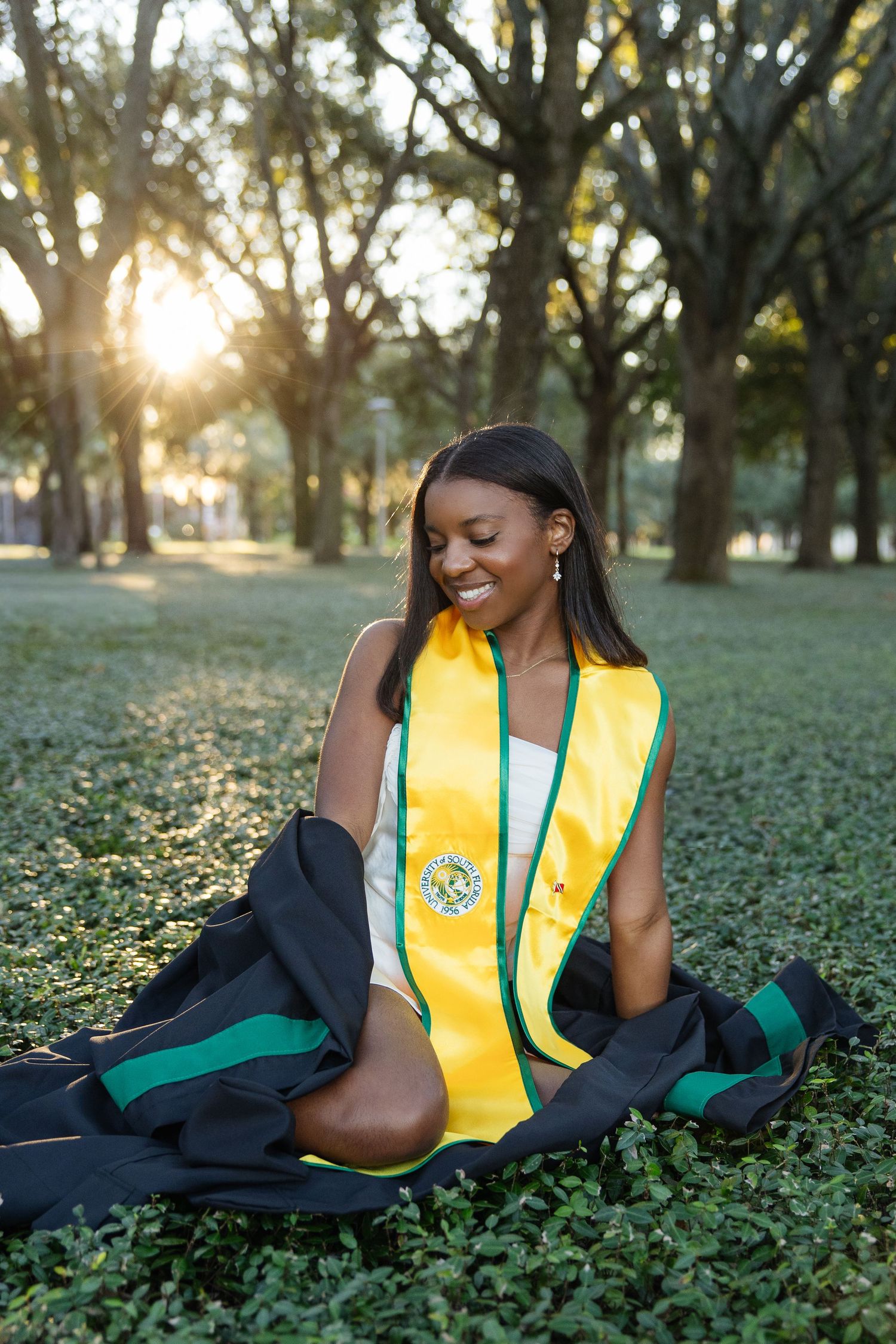 A University of South Florida graduate poses in the grass taken by Tampa grad photographer Michaela Gom Photography.